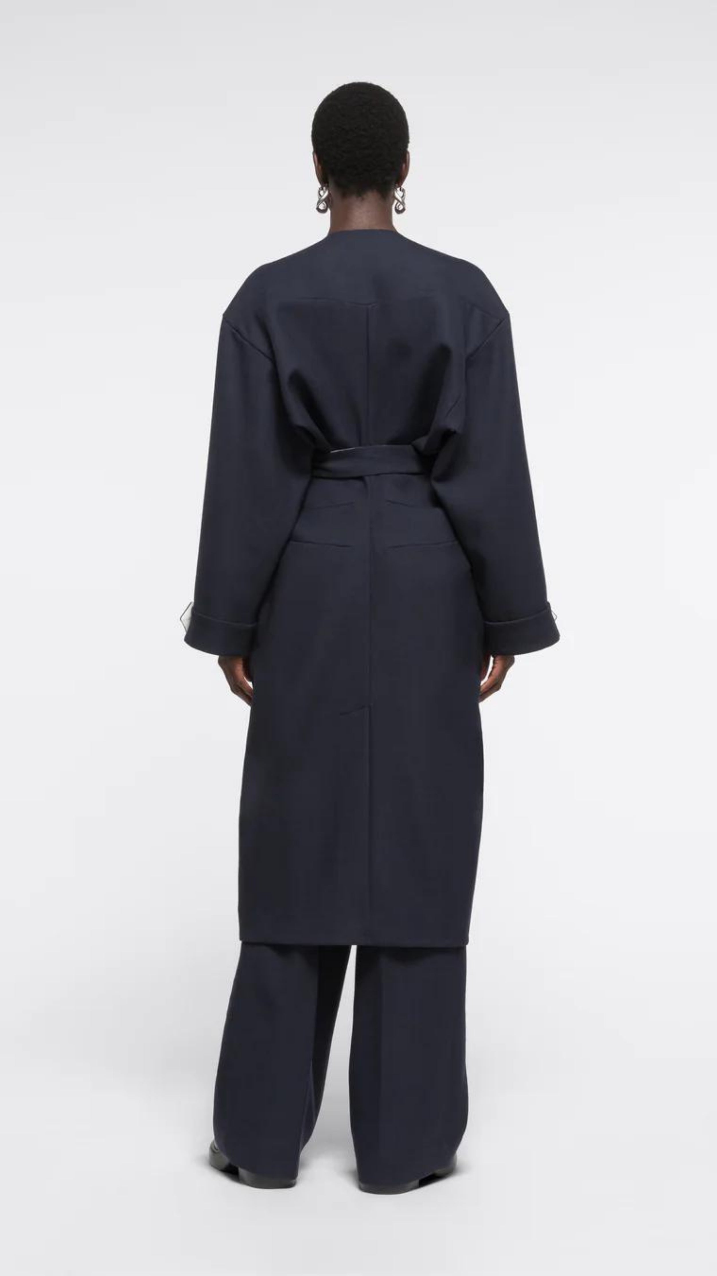 AZ Factory Colville Molly Molloy Lucinda Chambers, Draped Wool Coat in Navy. Wrap around wool coat made in Italy in navy blue. It has an ecru lining and can be worn open or belted for a more fitted style. Shown on model from the back.