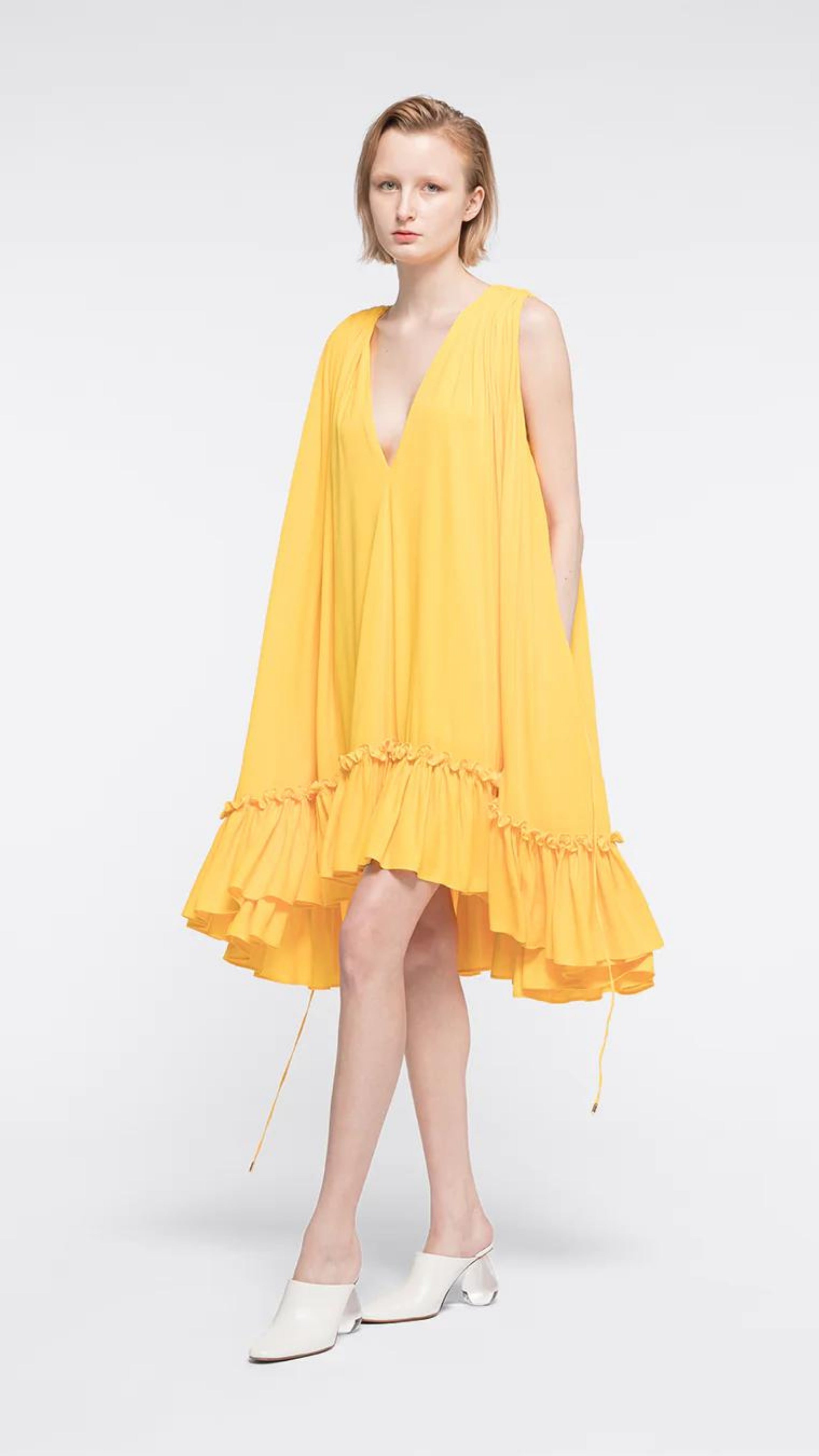 Az Factory Lutz Huelle Marilyn Dress. Bright yellow summer dress in trapeze style. With a v neck and volumnous a-line body and ruffled bottom. Shown on model facing front.