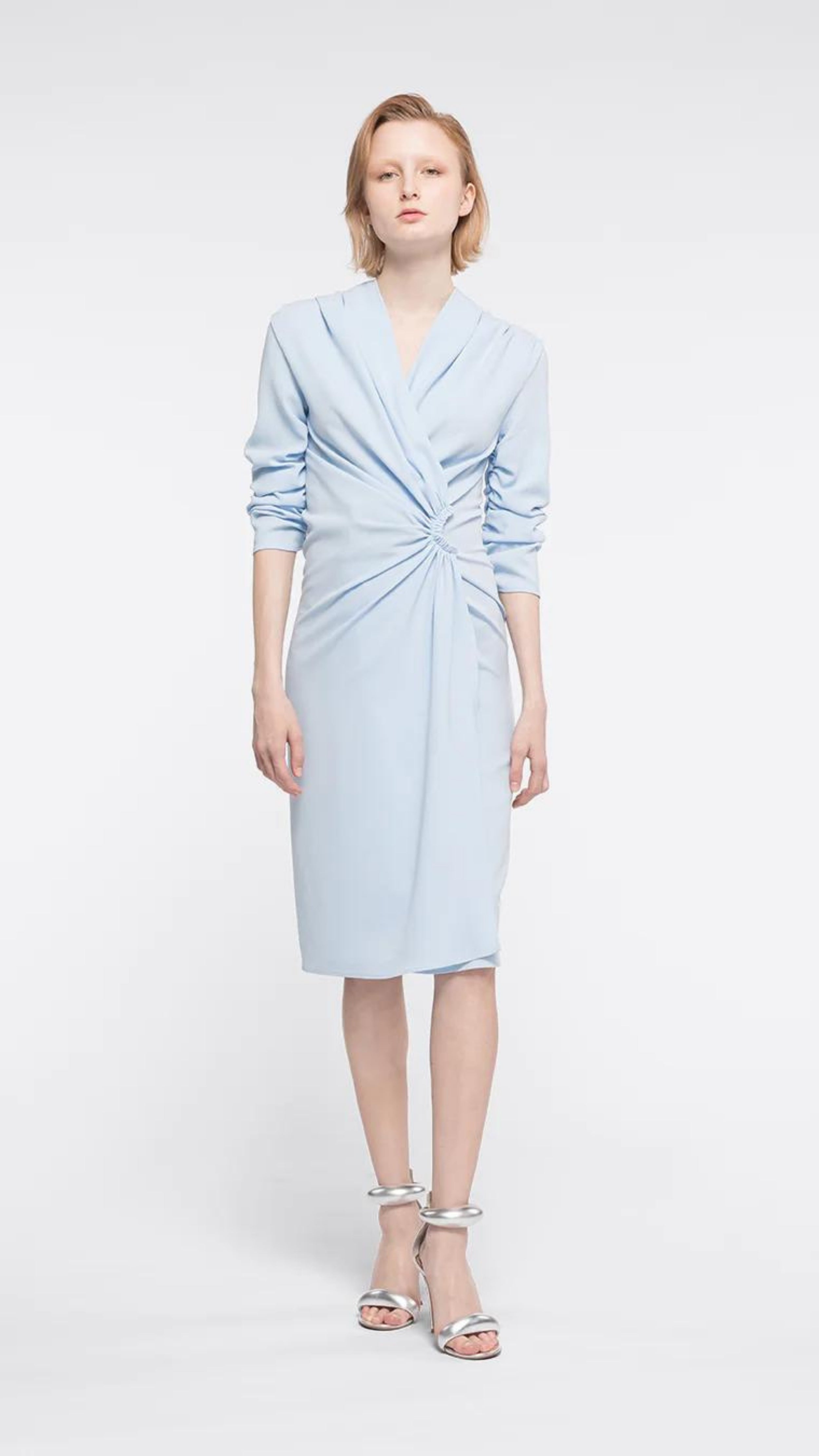 AZ Factory Lutz Huelle, Ella Dress. Crafted with a crepe texture in sky blue hue. V neck and draped, off center gathered front. Half length ruched sleeves  with a midi length skirt. Shown on model facing front