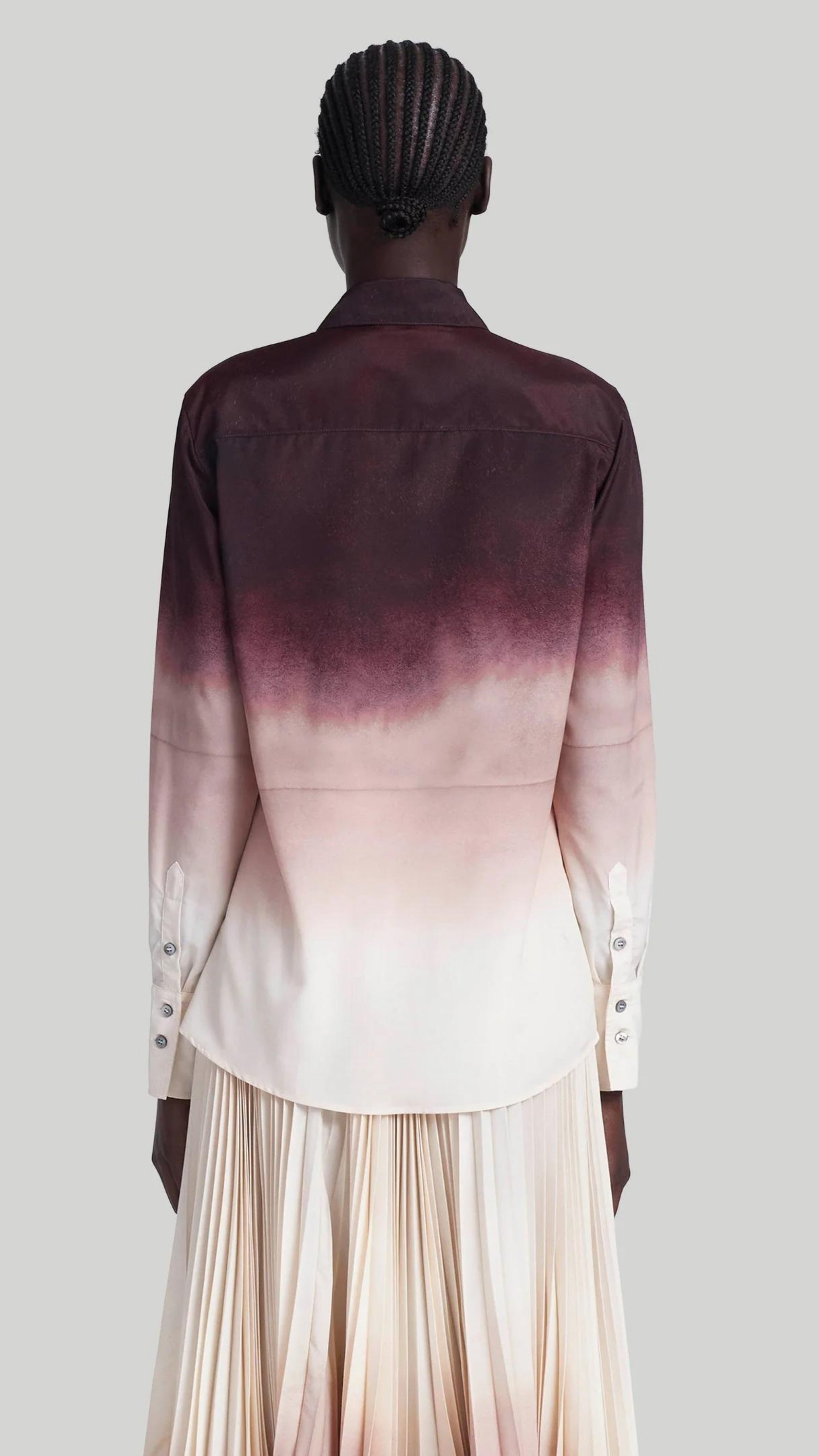 Altuzarra The Chika Top is crafted from Italian silk in an elegant cranberry to ivory dip dye ombre. The classic style button down shirt features a small point collar, concealed button front closure, and long cuffed sleeves. Shown on model facing Back.