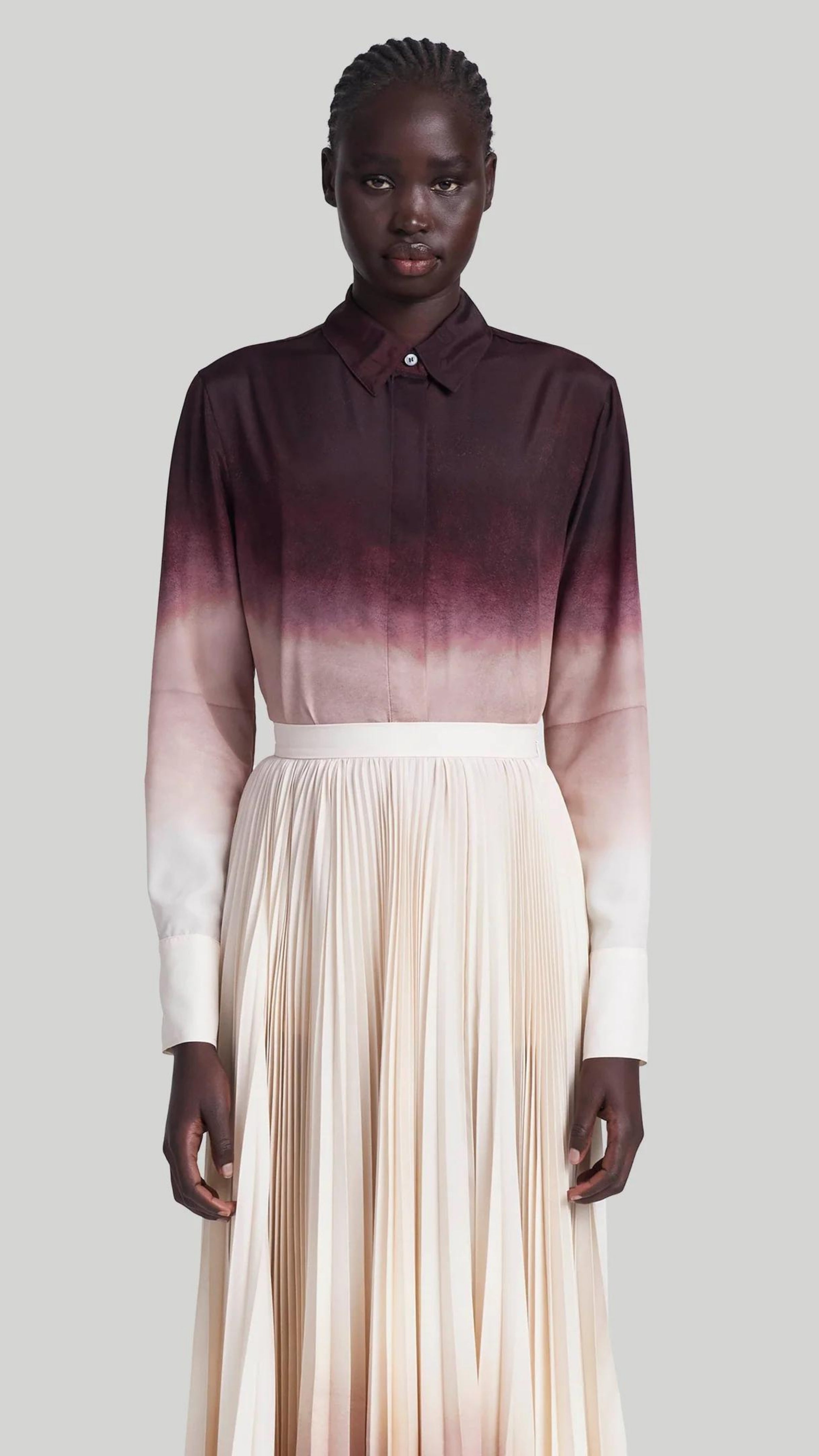 Altuzarra The Chika Top is crafted from Italian silk in an elegant cranberry to ivory dip dye ombre. The classic style button down shirt features a small point collar, concealed button front closure, and long cuffed sleeves. Shown on model facing front.