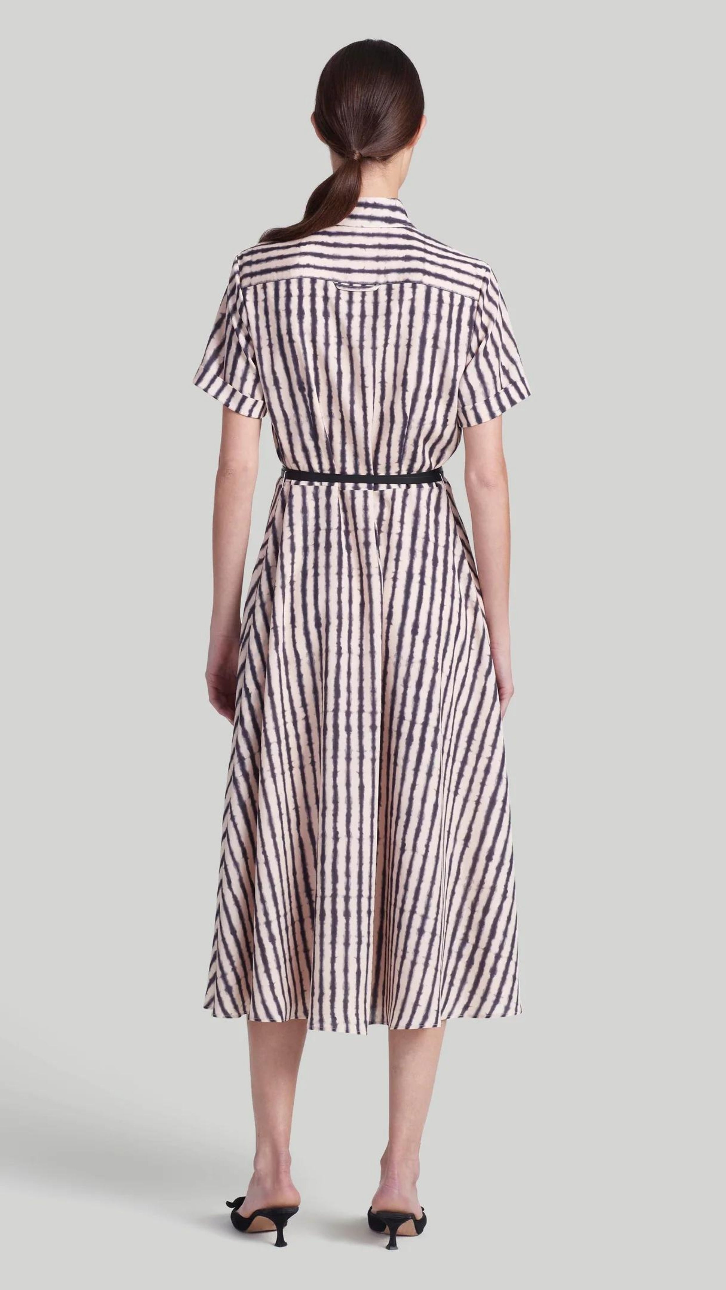 Altuzarra Kiera Dress The 'Kiera' dress is designed with a small point collar, short sleeves and a flattering A-line skirt. It is detailed with a slim leather waist belt and features a black and white stripe pattern and a front breast pocket. Shown on model facing back.