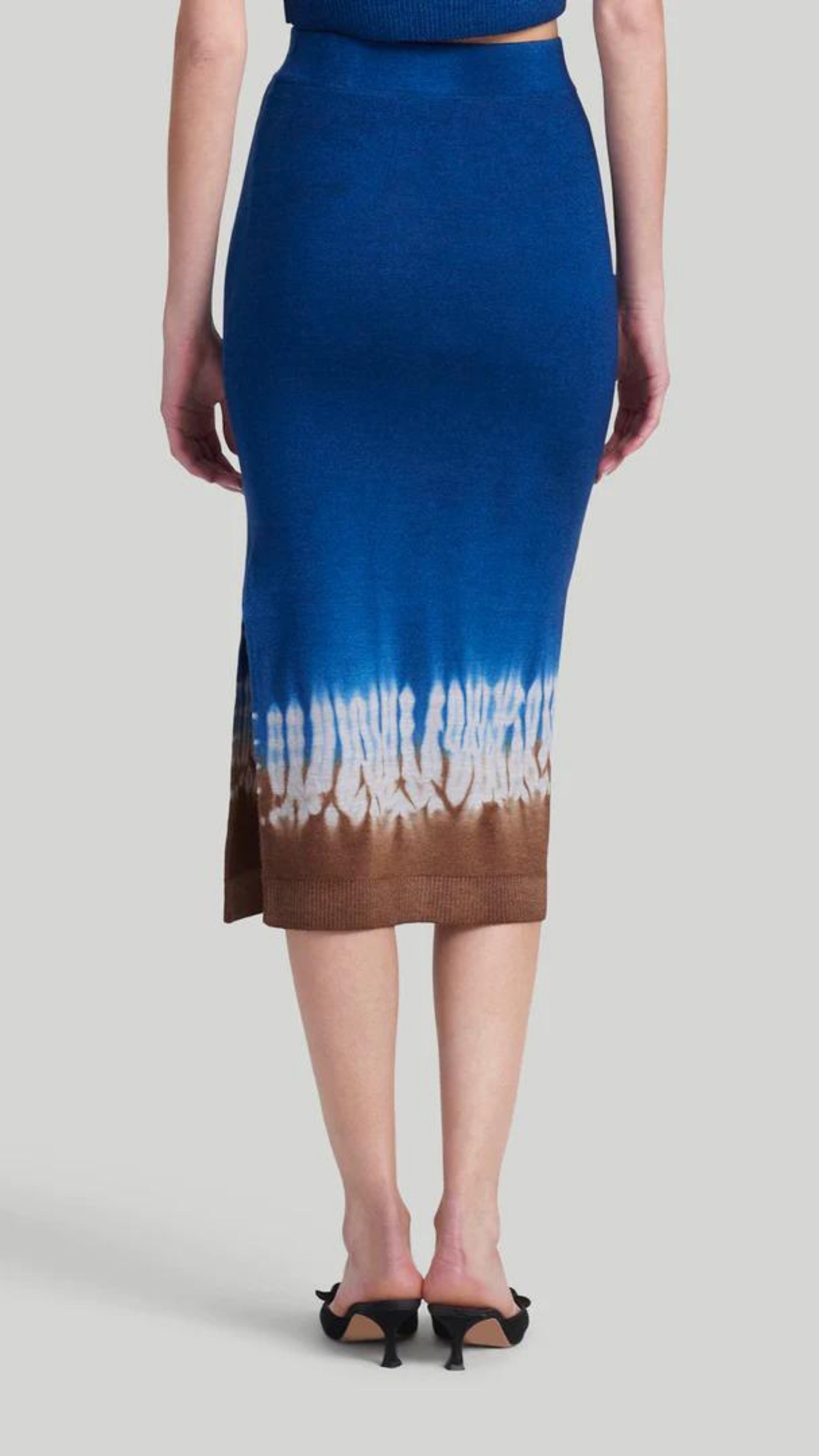 Altuzarra 'Morse' skirt, featuring Altuzarra's iconic Shibori tie-dye technique in brown, white, and blue. Made from 100% Superfine Merino 130's wool, this high-rise pencil silhouette midi length skirt. Shown on model facing back.
