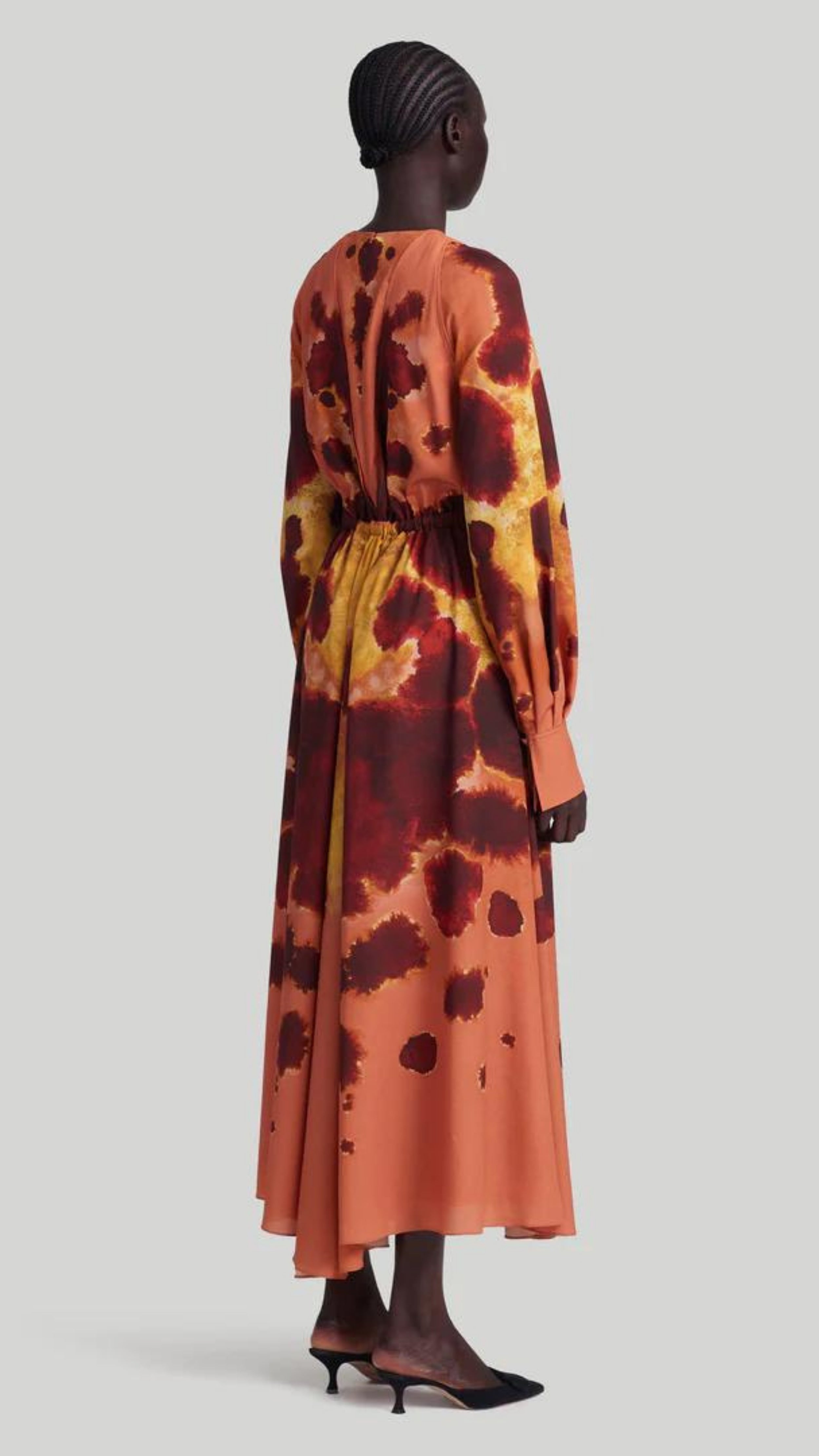 Altuzarra Peirene Dress. The Peirene midi dress has a relaxed silhouette with a tie at the waist. The keyhole neck can be styled closed or open, creating a v-neck look. Made in beautiful peach, cranberry, and yellow dyed pattern. Shown on model facing side and back