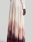 Altuzarra Sif Skirt A tailored maxi skirt with a straight high waistband and a voluminous pleated skirt. Made from 100% Italian silk it is dip dyed in an ombre of in cranberry to ivory coloring. On model facing back.