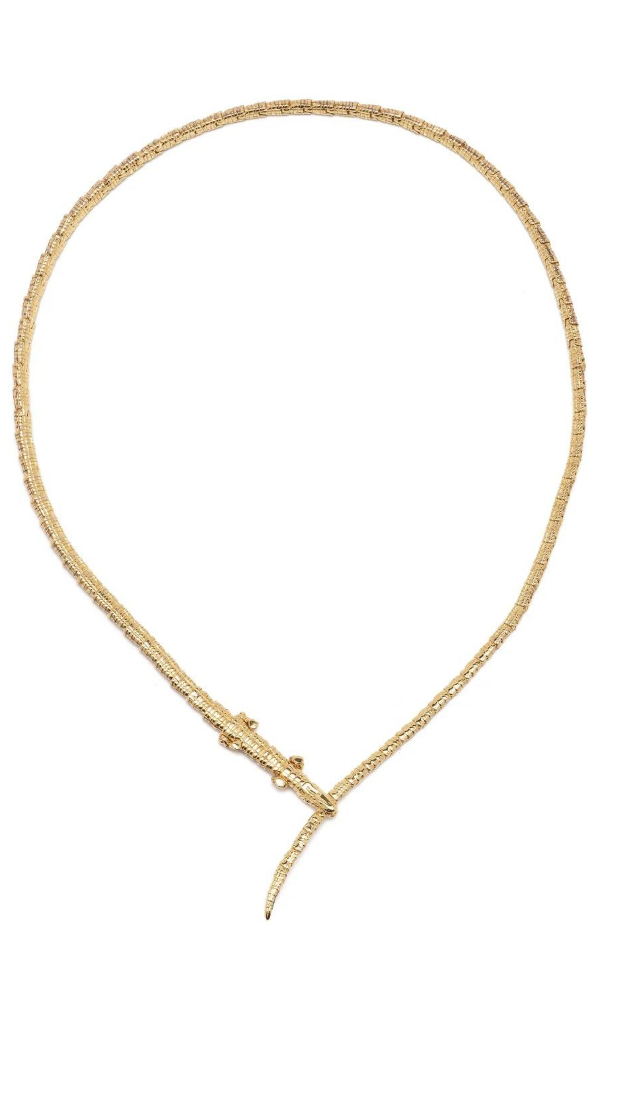 Bibi van der Velden The Alligator Wrap Thin Necklace made from 18k yellow gold in the shape of body of an alligator. Its elongated tail serves as the necklace's length and features a closure of the alligator's jaws snapping down on its own tail in the front. This necklace has  tsavorite eyes and moving feet. Shown on from the top