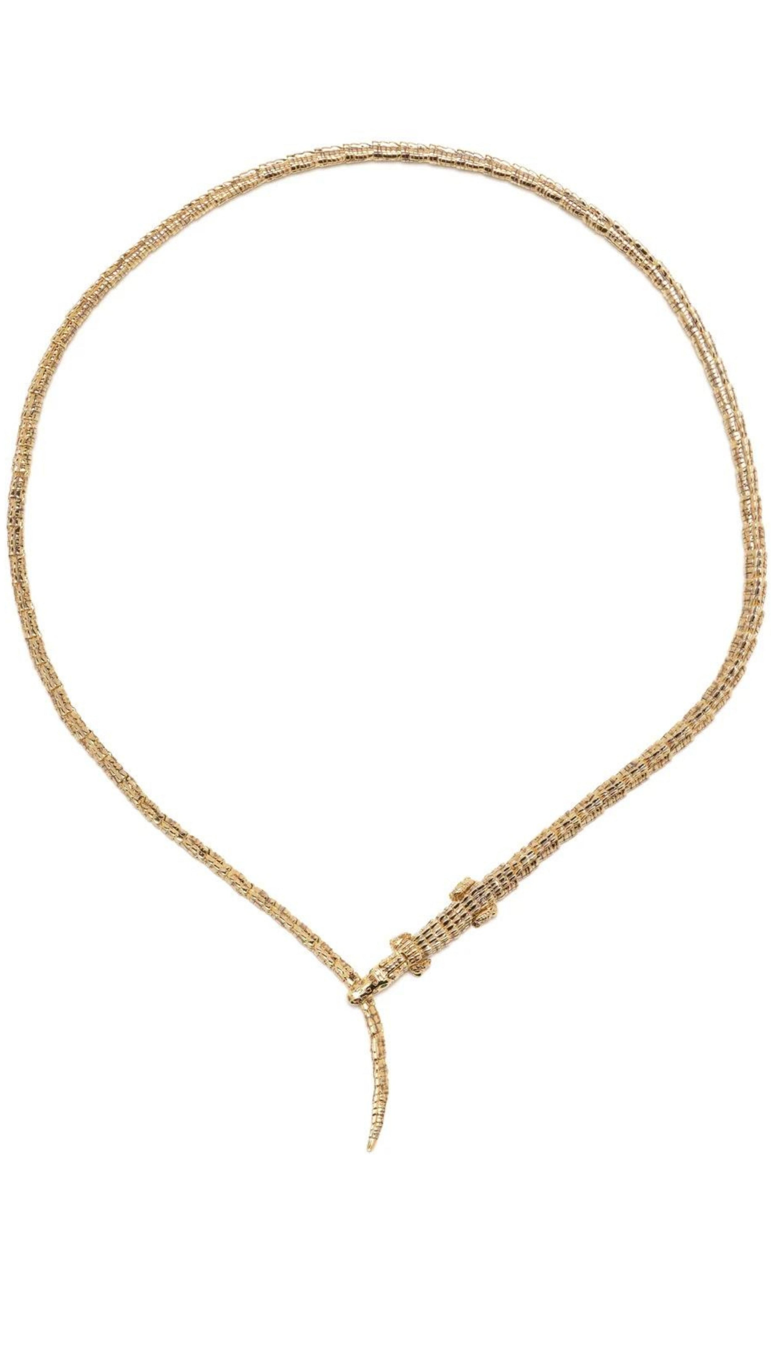 Bibi van der Velden The Alligator Wrap Thin Necklace made from 18k yellow gold in the shape of body of an alligator. Its elongated tail serves as the necklace's length and features a closure of the alligator's jaws snapping down on its own tail in the front. This necklace has  tsavorite eyes and moving feet. Shown from the top.