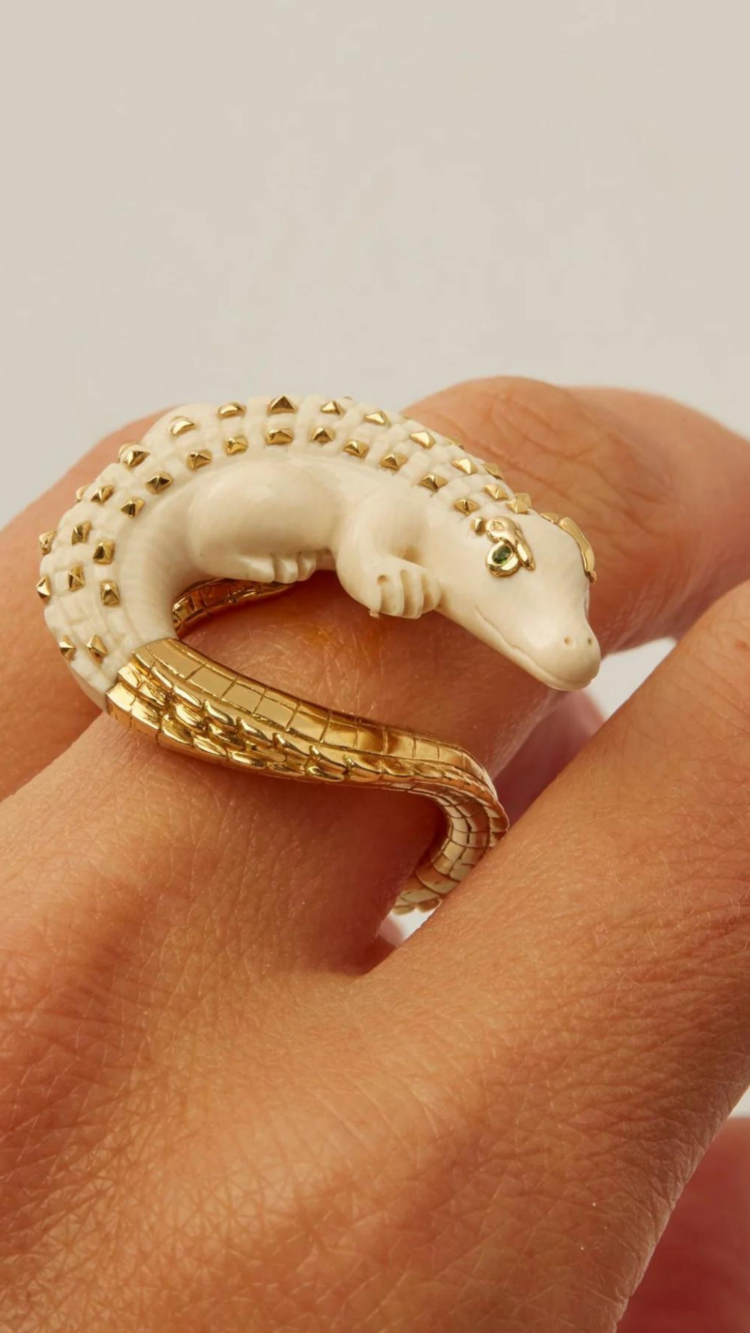 Bibi van der Velden Mammoth Alligator Twist Ring. Crafted in mamoth tusk in the shape of an alligator that curves around the finger. The tail is made from 18K gold and the ivory body has 18K gold studs. The ring is shown on a model.