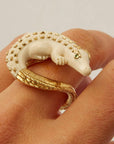 Bibi van der Velden Mammoth Alligator Twist Ring. Crafted in mamoth tusk in the shape of an alligator that curves around the finger. The tail is made from 18K gold and the ivory body has 18K gold studs. The ring is shown on a model.