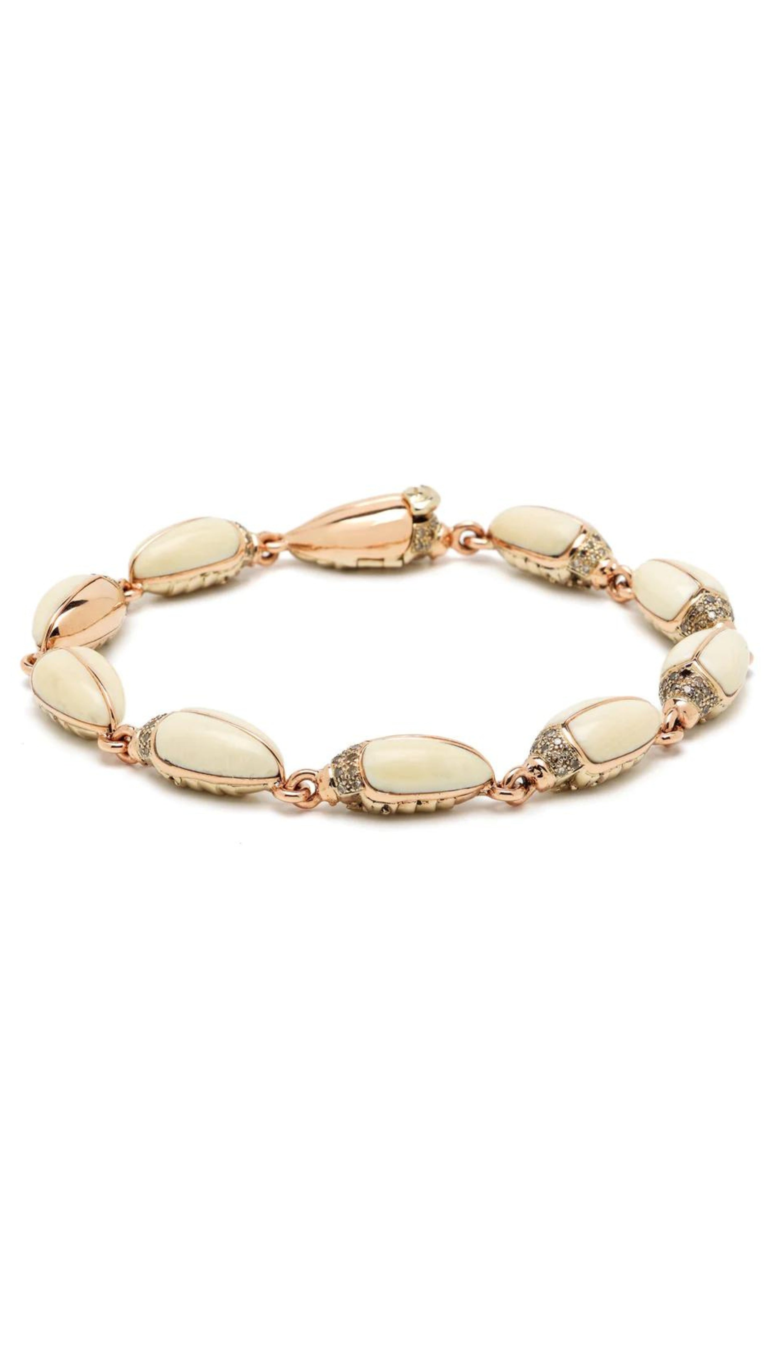 xWinter Mammoth Scarab Bracelet is made from creamy tones of polished and carved mammoth tusk, 18k yellow gold, 925 sterling silver, and brown diamonds. Individual scarabs are linked together. Shown from the side.