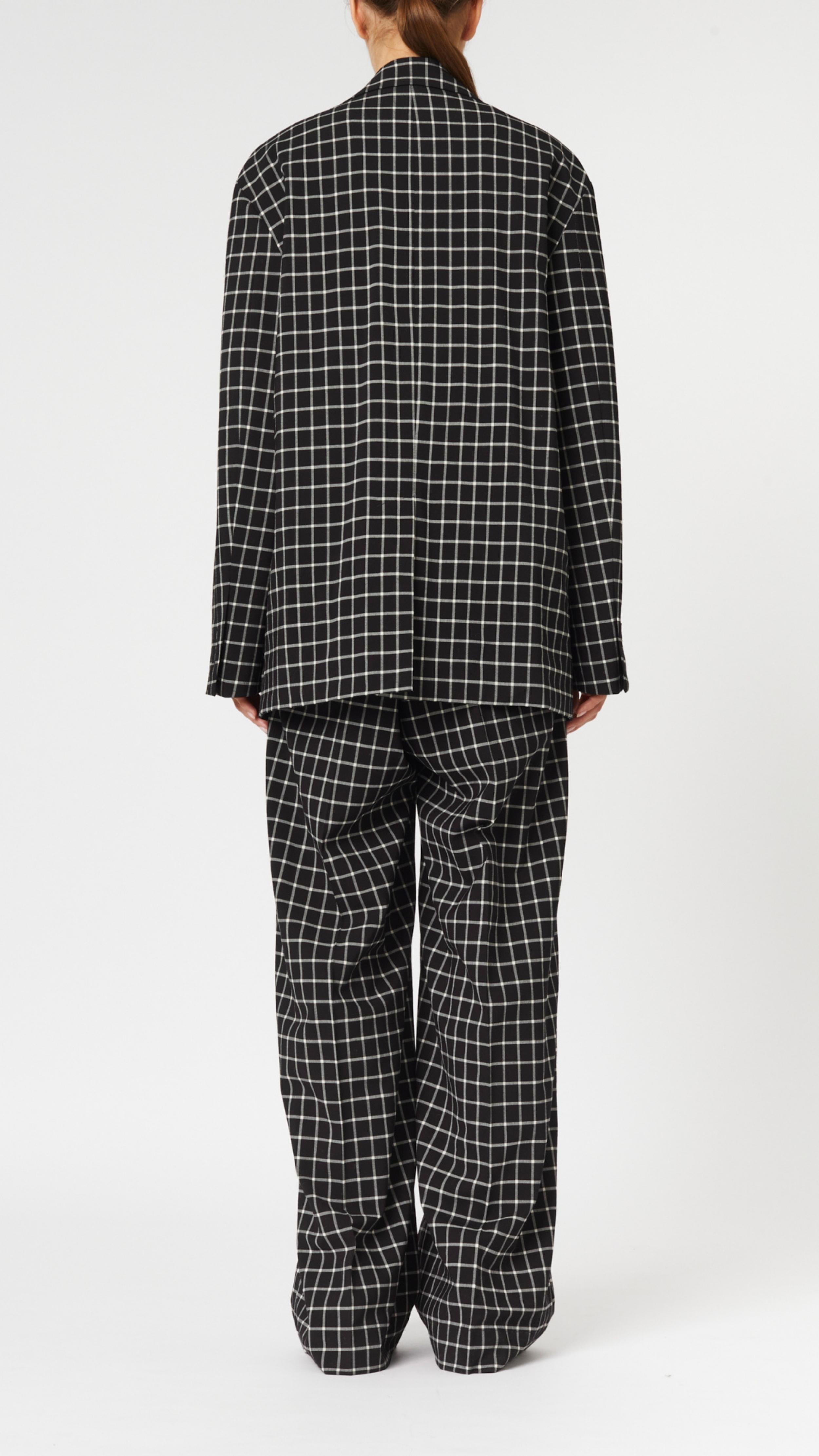 Plan C Checked Black Blazer. Modern suit jacket option in an oversized fit in lightweight wool. Classic black and white check pattern. Shown on model facing to the back.
