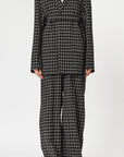Plan C Checked Black Blazer. Modern suit jacket option in an oversized fit in lightweight wool. Classic black and white check pattern. Shown on model buttoned and belted. Facing to the front with coordinating Checked Black Trousers..