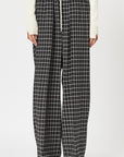 Plan C Checked Black Trousers. Loose fitting suit trousers with a drawstring adjustable waist in a classic black and white check patttern. Modern and oversized style. Shown on model facing front.