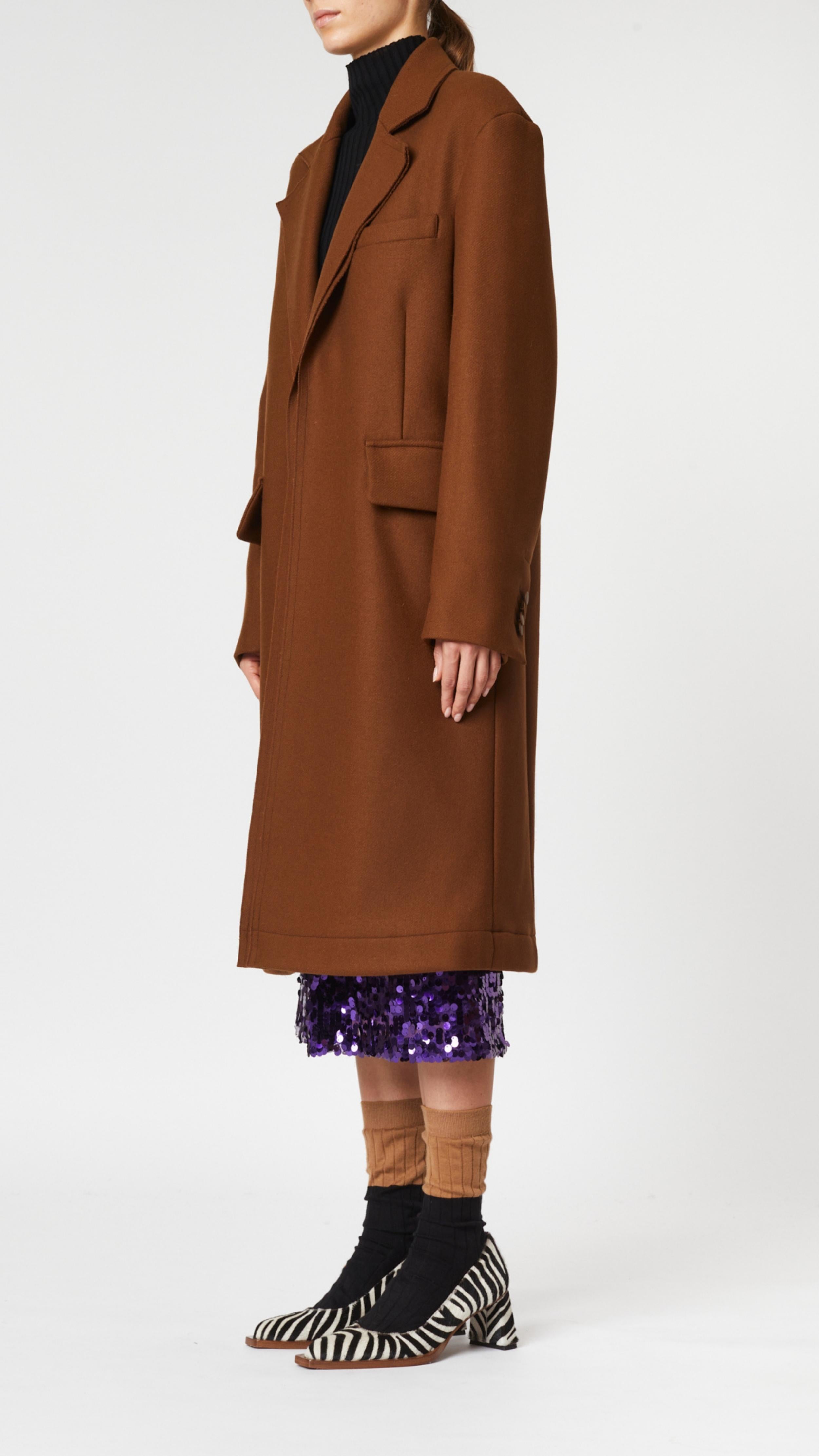 Plan C Chestnut Wool Overcoat. Classic but with a modern esthetic with coat jacket. Chestnut brown Italian wool with double layers. Midi length and long sleeves. Shown on model facing to the side.