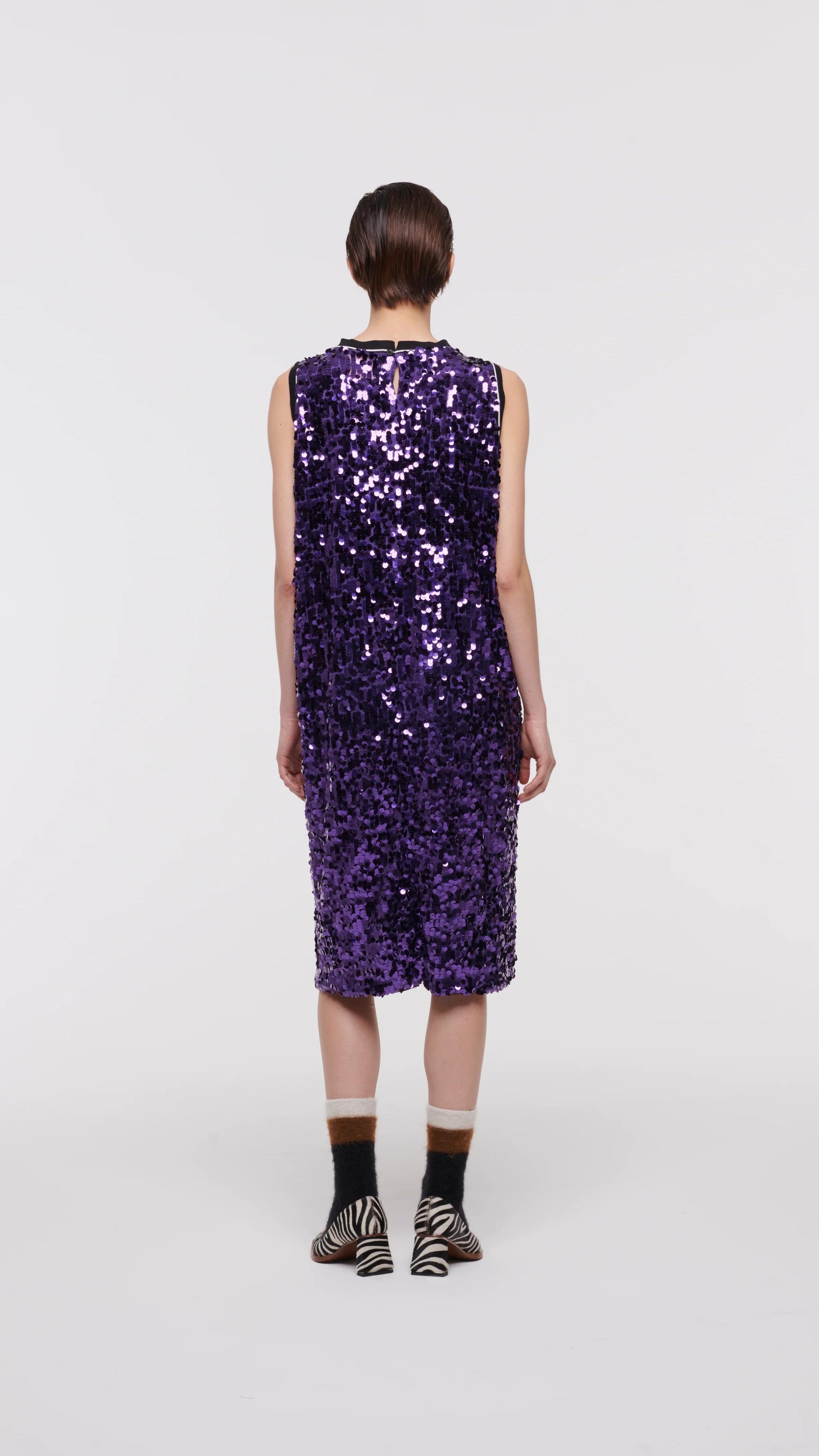 Plan C Color Block Sequin Dress. Sleeveless racer back style midi length dress in purple and lime green. Trimmed in black at the neckline and arms. The green sequins form a v shape in the front. Shown on model facing back.
