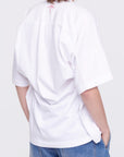 Plan C Draped Back White Cotton Tee 100% cotton, classic white tee with an updated modern draped back. The iconic Bianca patch in bold red adds a discreet accent at the back neckline. Shown on model from the back.