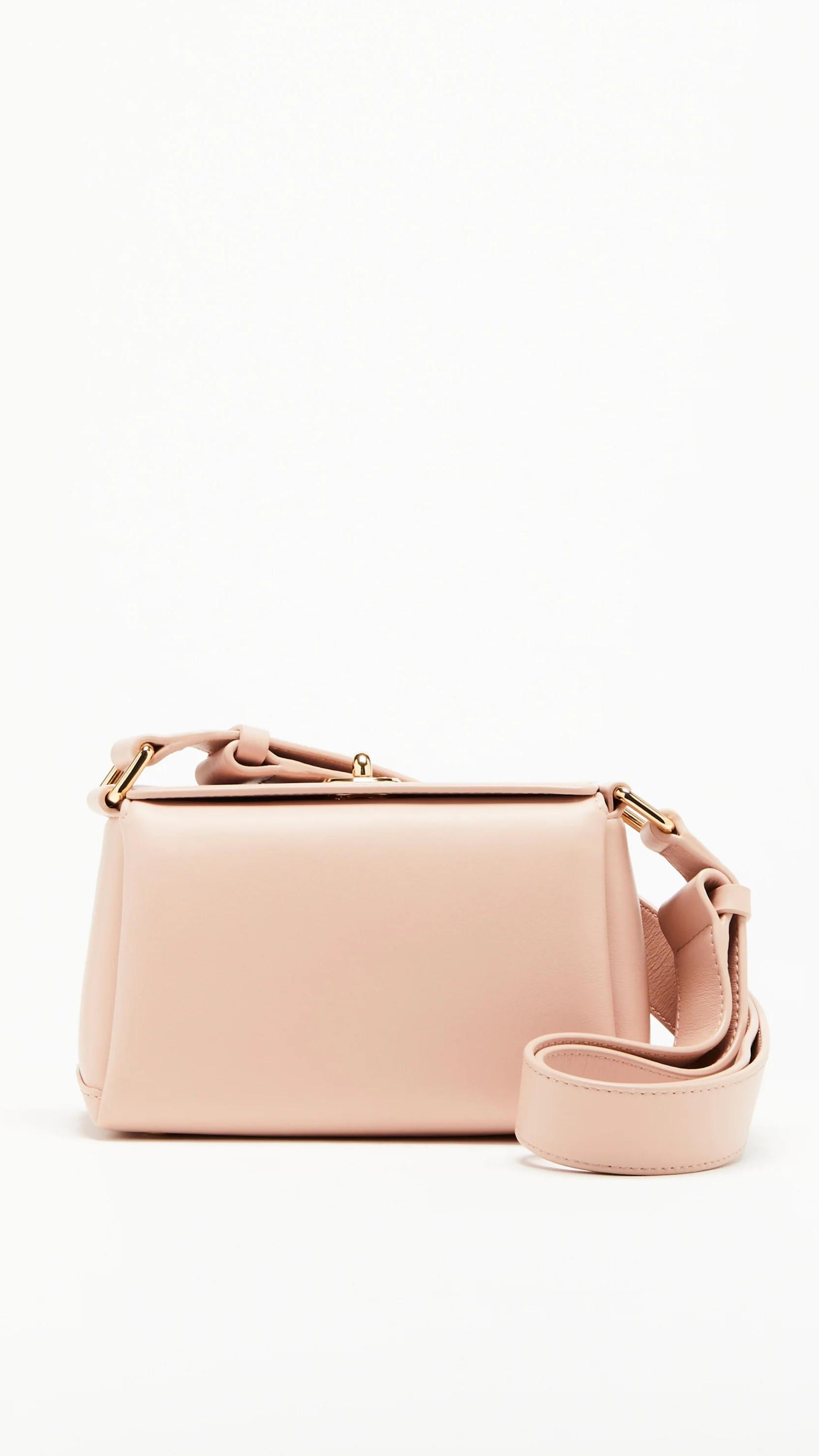 Plan C The Mini Folded Bag in Sand Pink. Luxury handbag crafted in Italy from soft calfskin with an adjustable leather shoulder strap. This purse has a gold-toned turnstile top closure and offers three compartments, one flat zipped and one snap buttoned pocket. Photo shown from the front view.