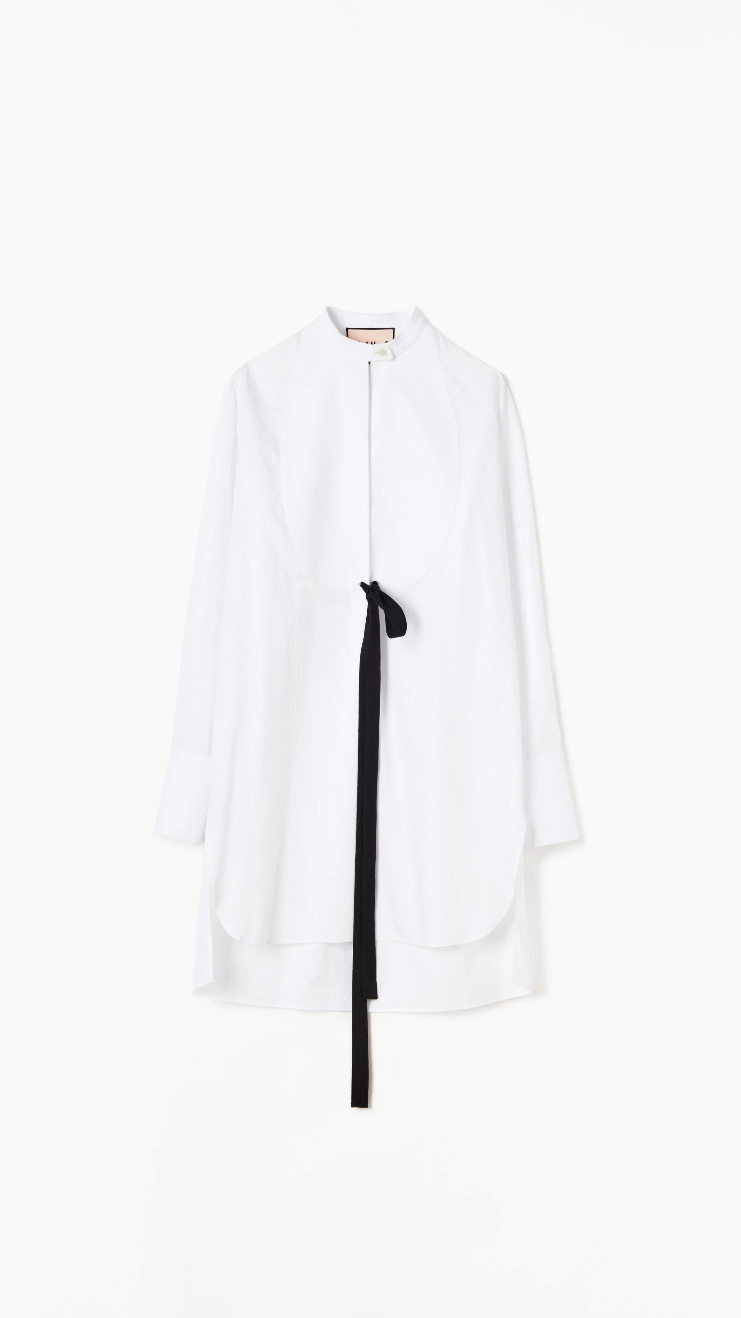 Plan C White Sartorial Poplin Shirt. Classic with a twist long white poplin blouse with front buttons. An added black ribbon detail in the front. Oversized cuffs at the long sleeves. Product photo shown from the front.