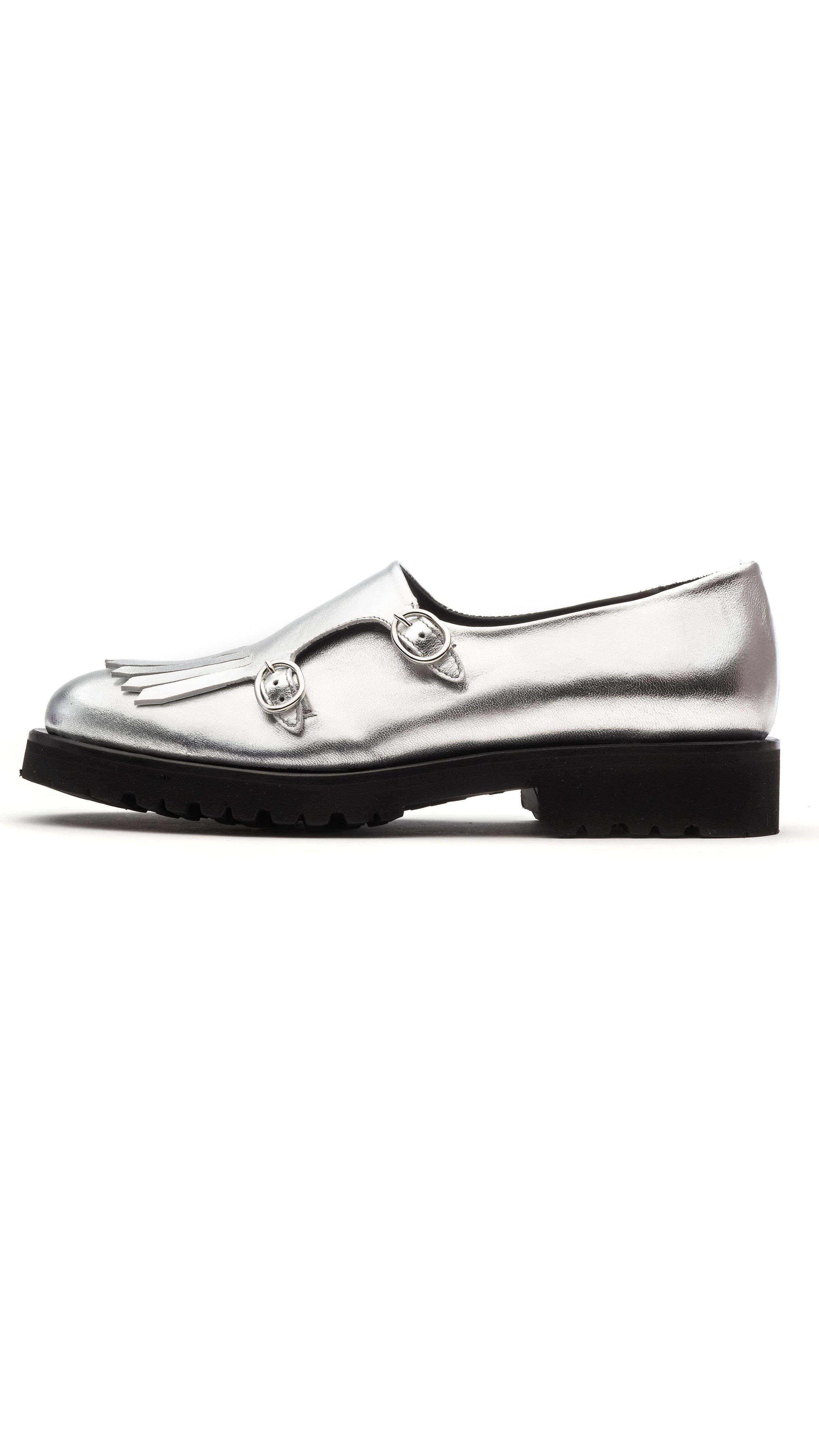 The Cedar Brogues are handcrafted in Italy with luxurious soft metallic silver calf skin. They have side buckles and fringing to the toe for a distinctive finish. The 10mm platform heel. Photo facing the side