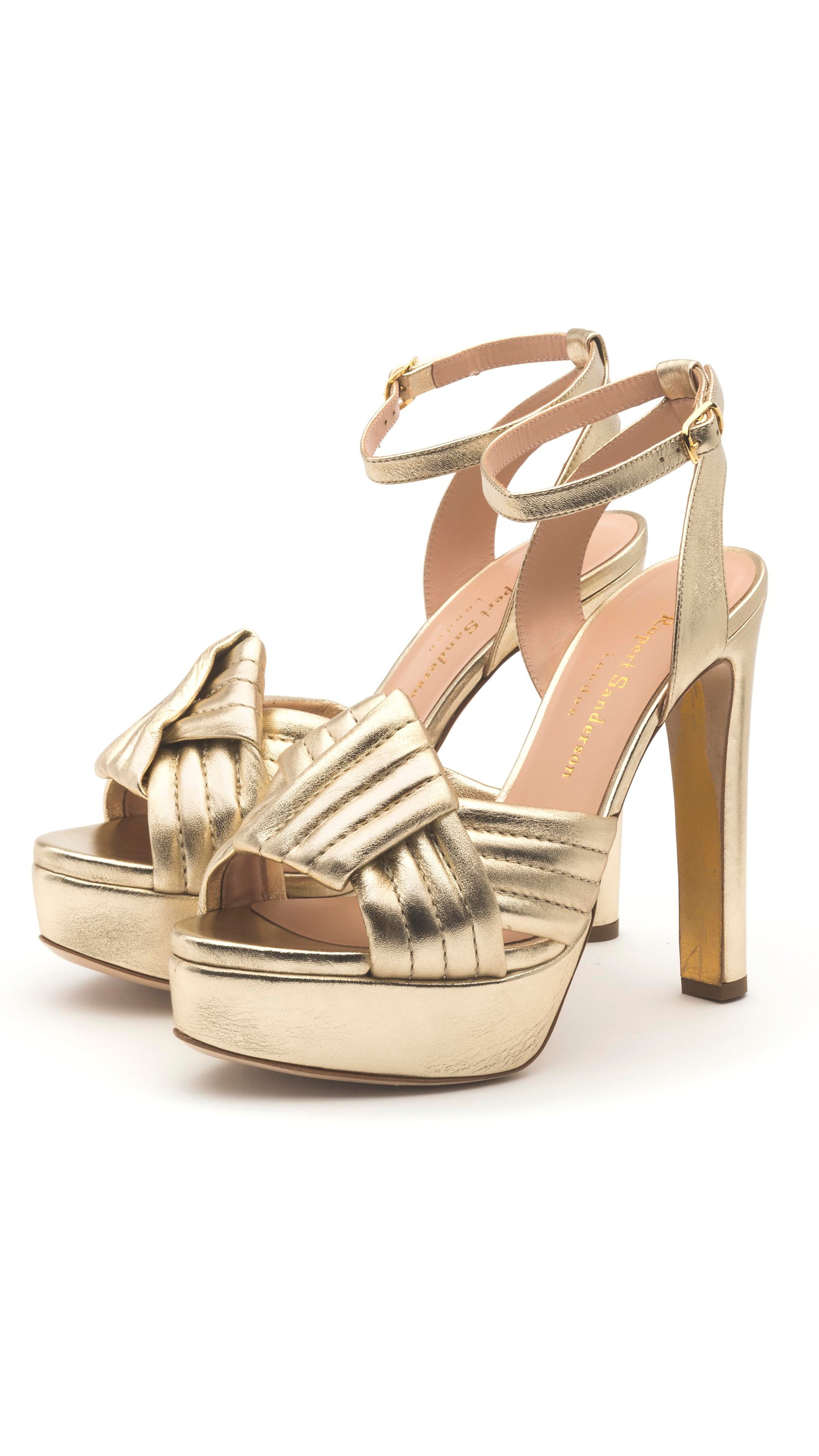Rupert Sanderson, The Hellcat Heel Crafted in the highest quality Italian Nappa leather and complemented by a woven geometric pattern across the toes in a soft metallic gold color. The platform soles and ankle straps provide a secure fit to comfortably wear the 10cm heel.  Both shoes shown from the front side angle.