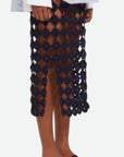 Wales Bonner Stanza Knit Skirt The Stanza Knit Skirt is crafted with an elastic waist and a straight body, falling just below the knee. It's made from a cotton and lycra blend open knit crochet in navy blue. Shown on model facing side.