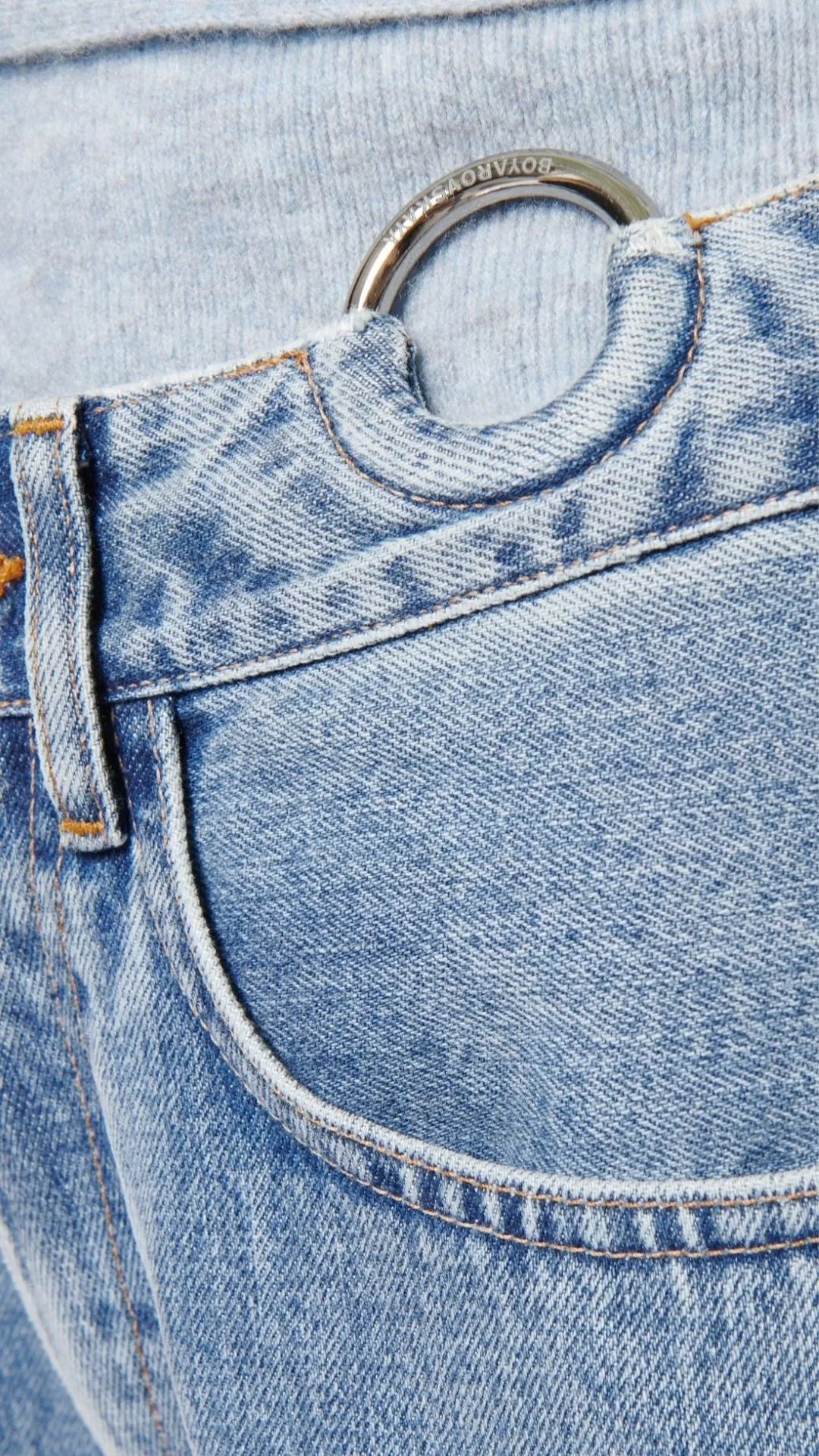 Boyarovskaya Slim Ring Jean. Light color stone denim with a slightly tapered leg and falls to just above the ankle. Zipper closure with silver ring detail on the front right. Photo of ring detail.