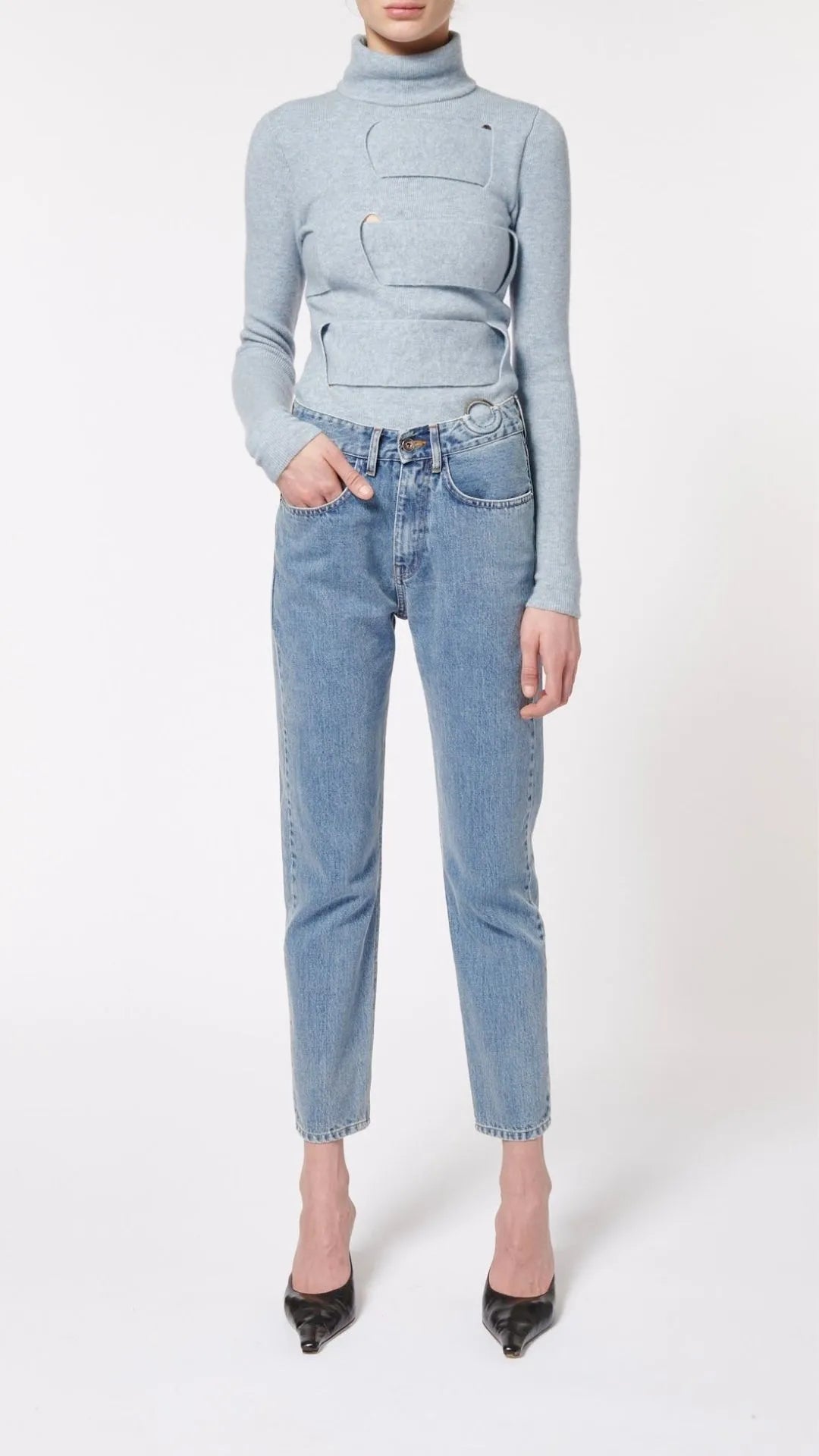Boyarovskaya Slim Ring Jean. Light color stone denim with a slightly tapered leg and falls to just above the ankle. Zipper closure with silver ring detail on the front right. Product shown on model facing front.