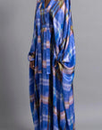 Thebe Magugu Blue Print Belted Kaftan. An elegant draped kaftan dress in blue with soft pink and grey striping. It features a V neck and can be belted to find the perfect fit for your body. It has long sleeves and is floor length. This photo shows the piece on the model facing to the front and side..