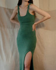 Alejandra Alonso Rojas Machine Knit Dress in Green. Crafted in the softest camel wool it is a form fitting dress with thin straps and falls to midi length. It has a slit to just above the knee on one side. Shows dress on the model.