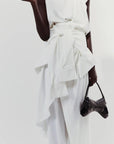 A.W.A.K.E. Mode Asymmetric Sleeveless Draped Top. White asymmetrical top. Beautifully draped in the front, with a slightly open back to one side. Shown on model facing the front.