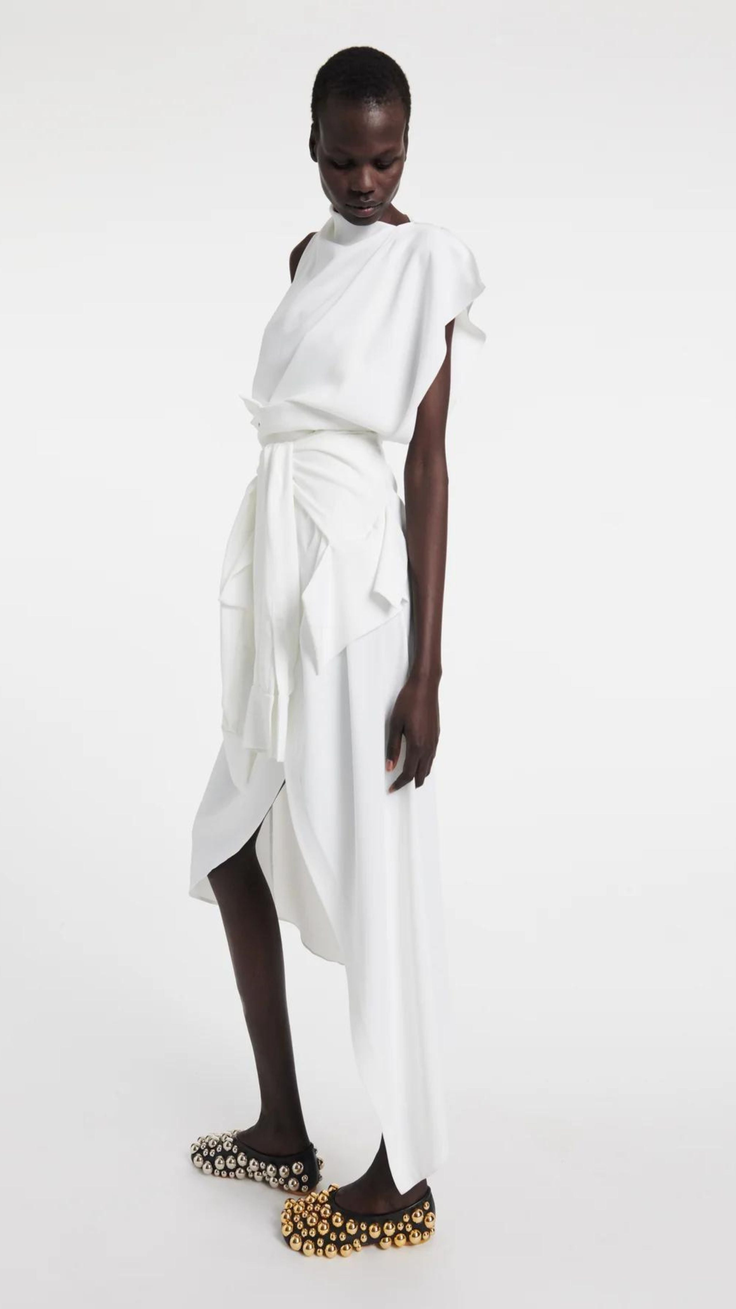 A.W.A.K.E. Mode Asymmetric Sleeveless Draped Top. White asymmetrical top. Beautifully draped in the front and pin tucked, with a slightly open back to one side. Shown on model facing the front.