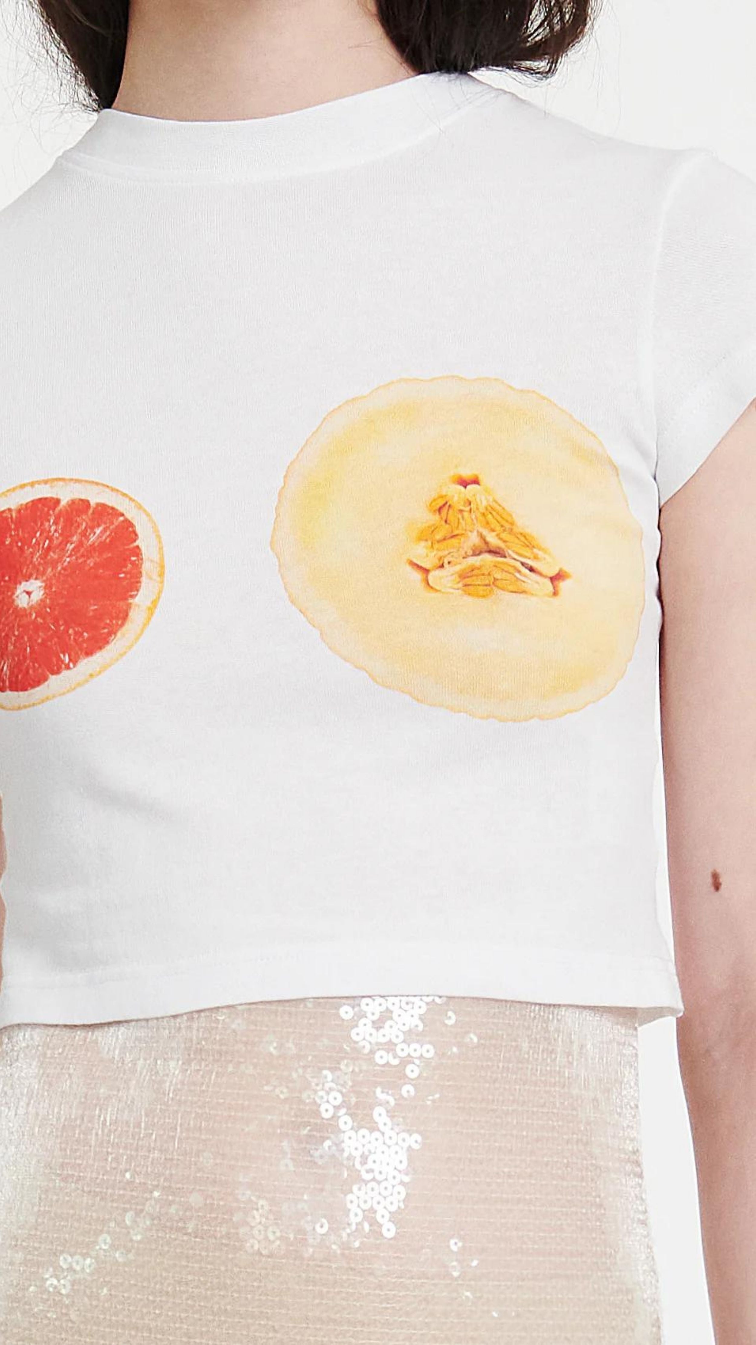 AWAKE Mode Cropped Fitted T-Shirt with Fruit Print. Cropped white tee shirt made from organic cotton with cap sleeves and a slim fit. The front shows grapefruit and melon at the chest. Close up photo of fruit print.