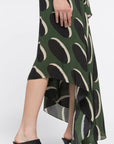 AZ Factory Colville Molly Molloy Lucinda Chambers. Crafted from a silky olive fabric, it features an elegant oval pattern in black and ecru. The front body is draped and it features an asymmetrical hemline that is shorter in the back and longer in the front. Detail of skirt asymmetrical hem.