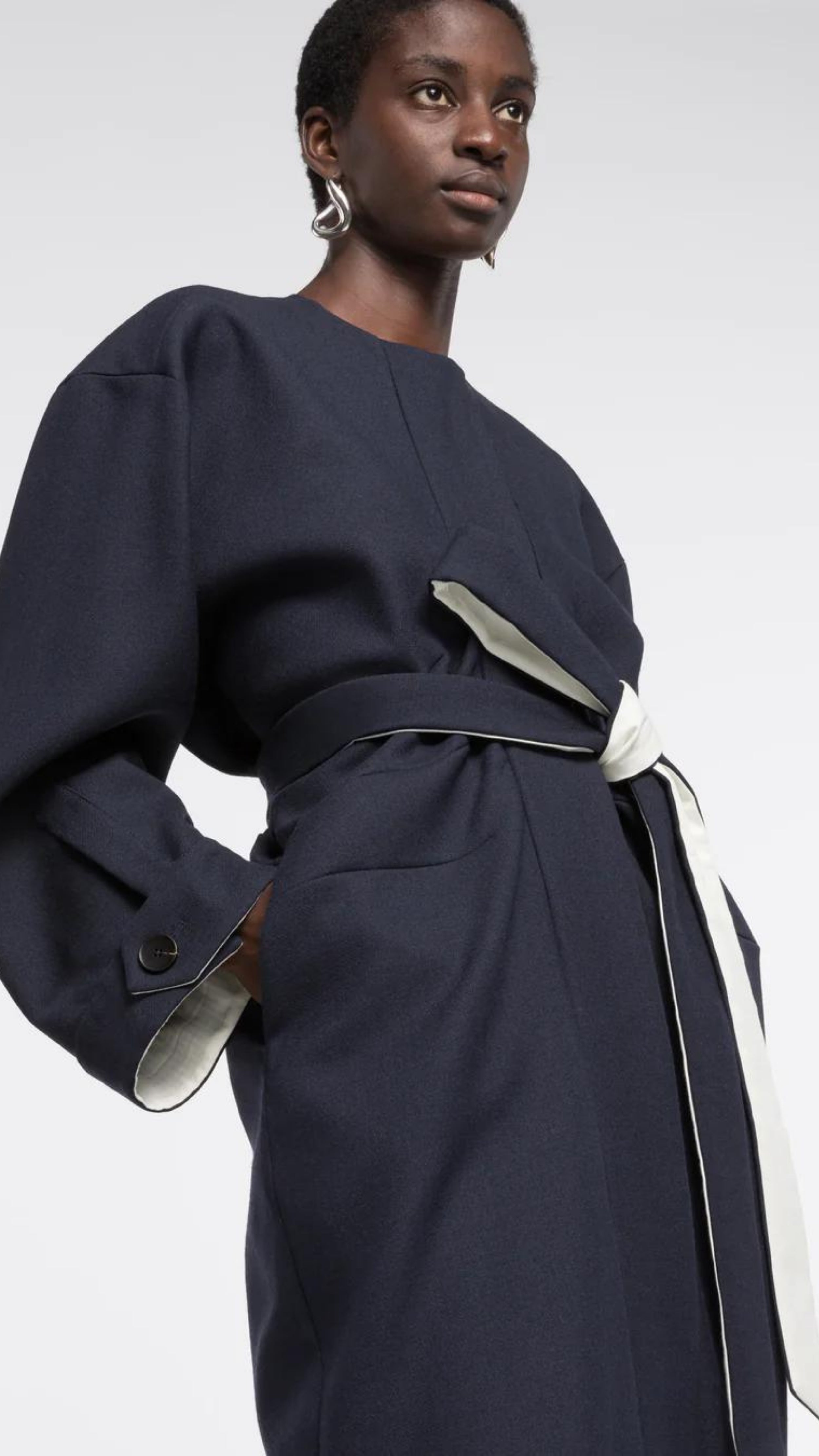 AZ Factory Colville Molly Molloy Lucinda Chambers, Draped Wool Coat in Navy. Wrap around wool coat made in Italy in navy blue. It has an ecru lining and can be worn open or belted for a more fitted style. Shown on model from the front with more detail.