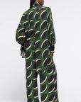 AZ Factory Colville Molly Molloy Lucinda Chambers, Pajama Pants in Khaki Macaroon Pajama loose style silky pants with elastic and drawstring waist band. Crafted in olive green with black and ecru oval pattern. Shown on model facing back.