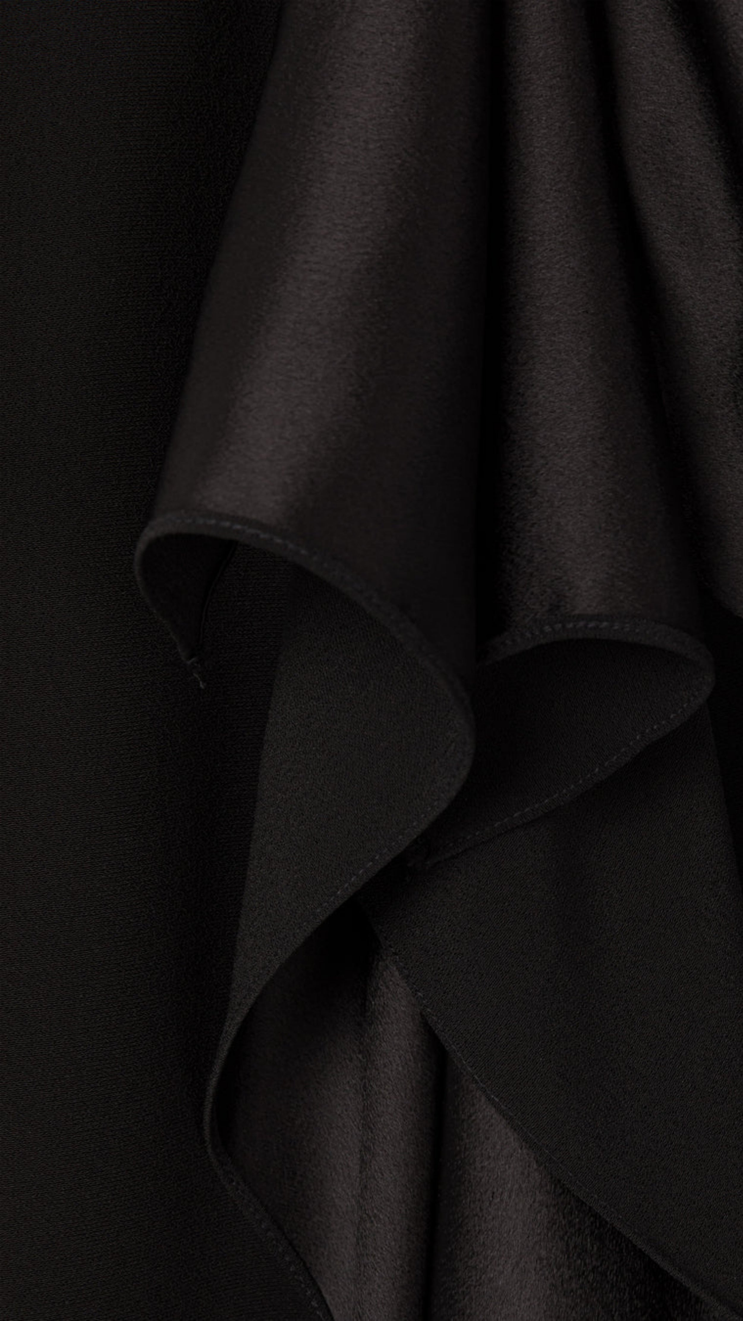 AZ Factory Colville Molly Molloy Lucinda Chambers, Ruffled Crepe Skirt in Black A sleek midi length skirt crafted from a mix of crepe and satin, complemented by a fold-over belt and delicate ruffling along the front panel. Close up of material fabric