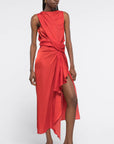 AZ Factory Colville Molly Molloy Lucinda Chambers, Sleeveless Draped Dress in Red An elegant red formal dress with a silhouette defined by a straight neckline and asymmetrical hemline. The waistline has detailed draping and the front leg as a slit. Shown on model facing front.