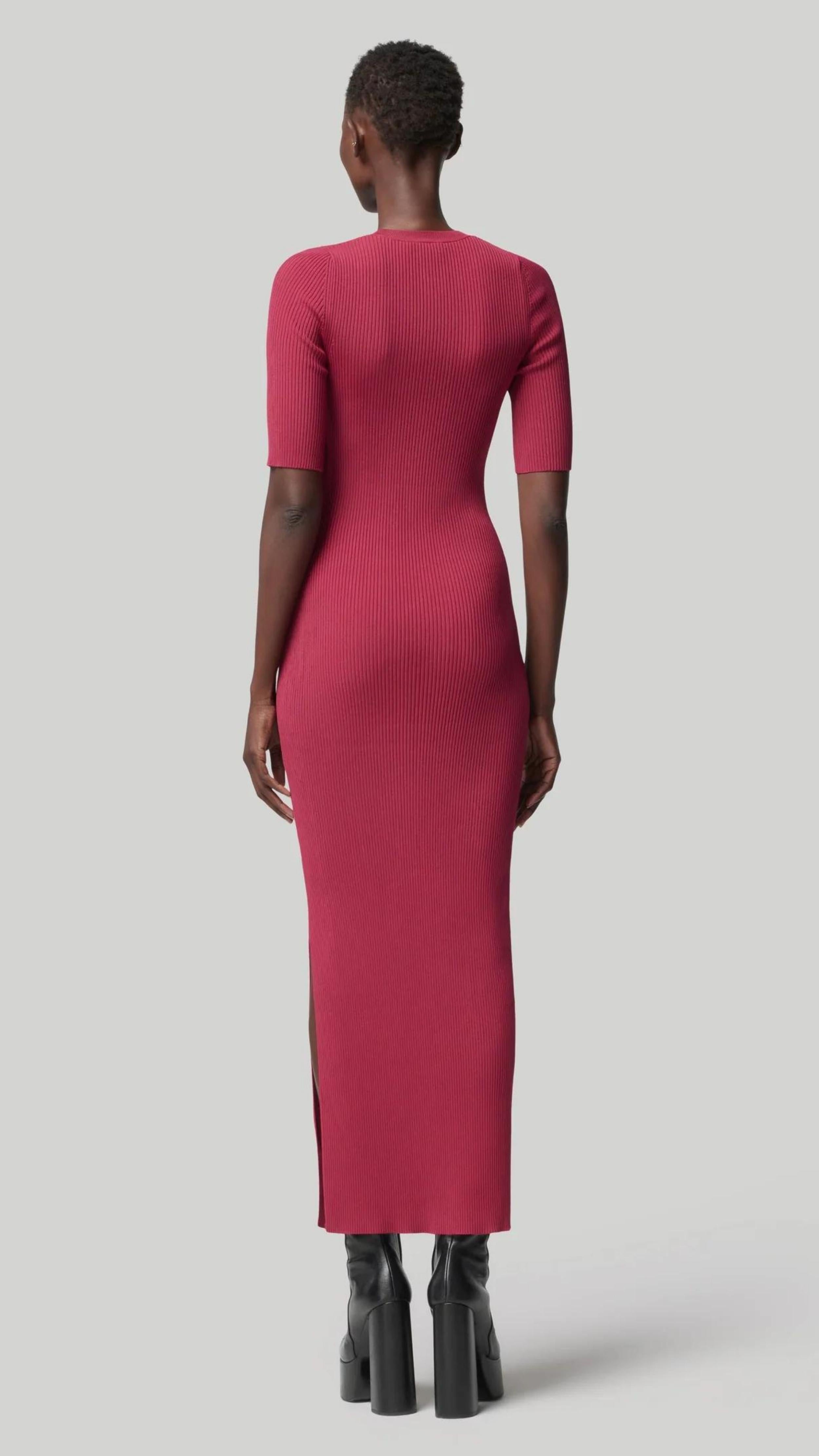 Altruzarra, Argolis Dress. Rose pink colored ribbed knit dress. Body hugging with flattering, slimming from waist detail. It has a rounded collar, half short sleeves and midid length. There are two side slits to the knee. Shown on model facing back. Available at experience 27 in madrid spain.