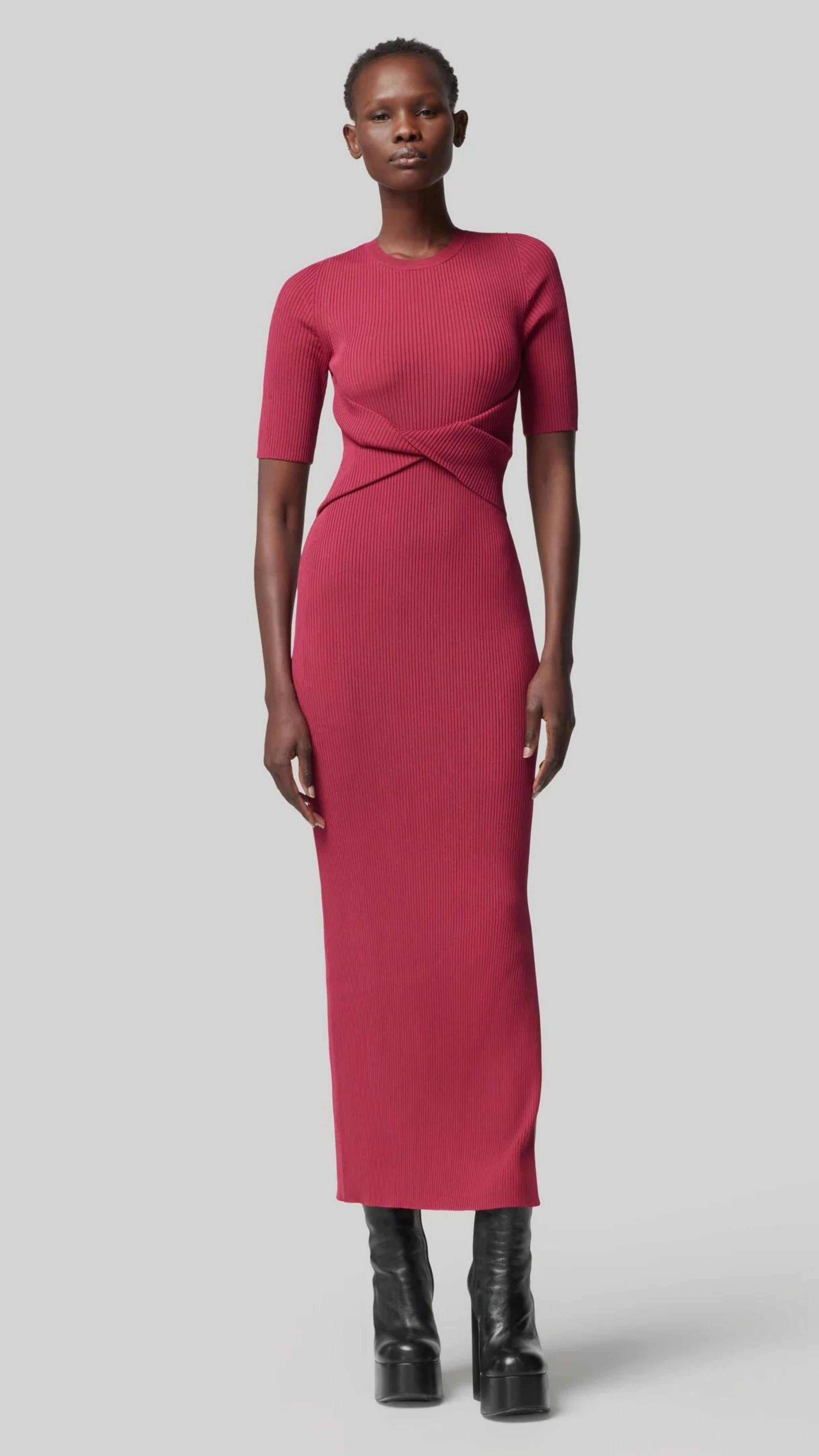 Altruzarra, Argolis Dress. Rose pink colored ribbed knit dress. Body hugging with flattering, slimming from waist detail. It has a rounded collar, half short sleeves and midid length. There are two side slits to the knee. Shown on model facing front. Available at experience 27 in madrid spain.