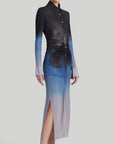 Altuzarra Claudia Dress in Eventide Made from jersey fabric, it is a slim-fitting midi dress featuring ruched detail at the waist, shirt dress buttons up the front, and side slits at the hem. The color is an ombre of deep grey, blue, and pale grey. Shown on model facing front side.