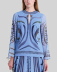 Altuzarra Crete Top. Silk hand painted top in tones of blues, greens and purple. Long sleeve loose style with eye hook at the neck line to wear open or closed. Shown on model facing front.