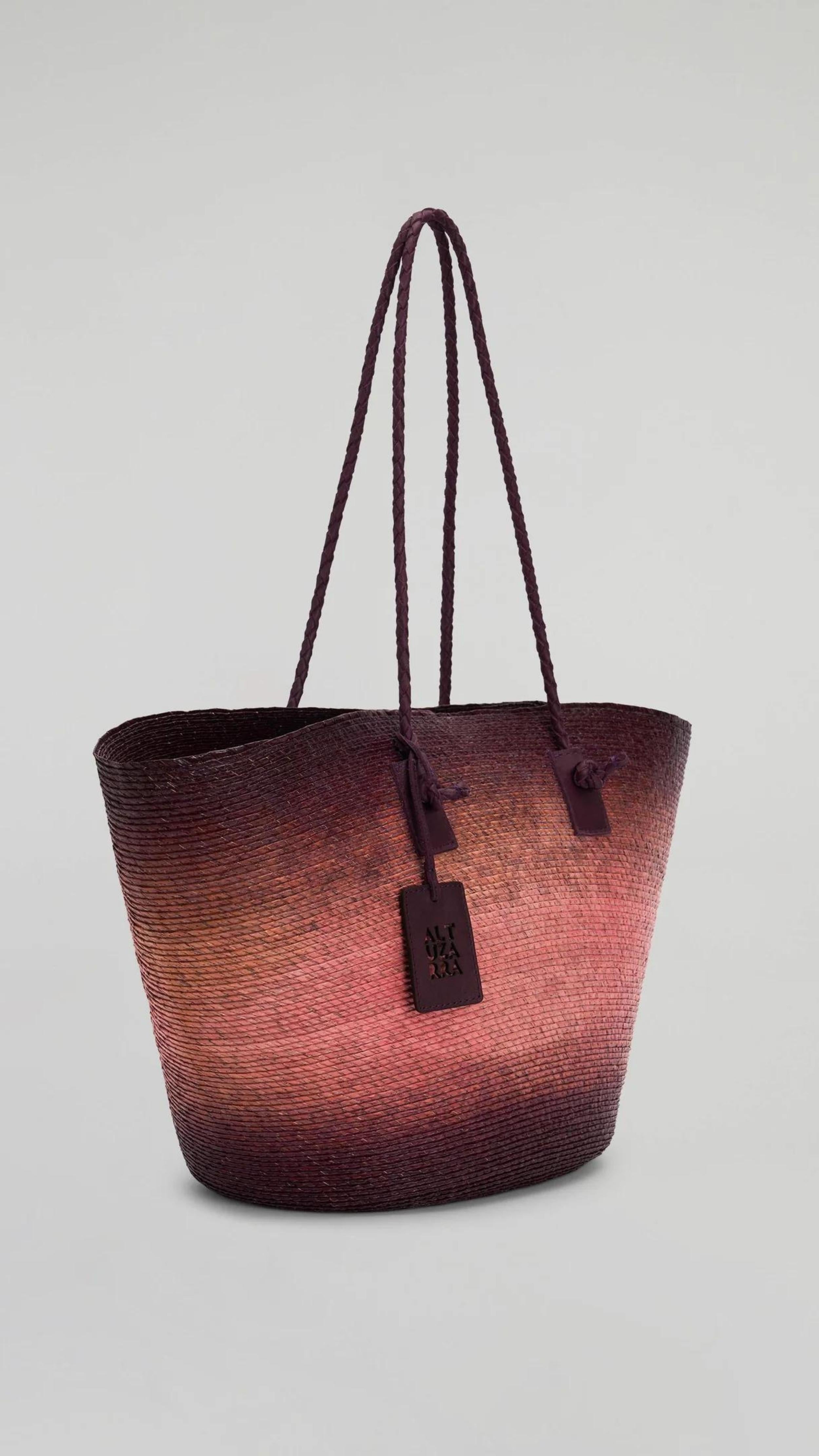 Altuzarra Large Watermill Bag in Orseille Landscape. Oversized raffia tote bag in pink and deep burgundy ombre colors. Woven raffia and palm with burgundy braided leather details. Available at experience 27 in madrid spain.