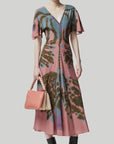 Altuzarra Pelopenese Dress. Rose pink, sky blue and green rorschach pattern midi dress. With a v neckline and soft draping half sleeves. Flowing skirt with waist line rouching. Shown on the model facing foreward.