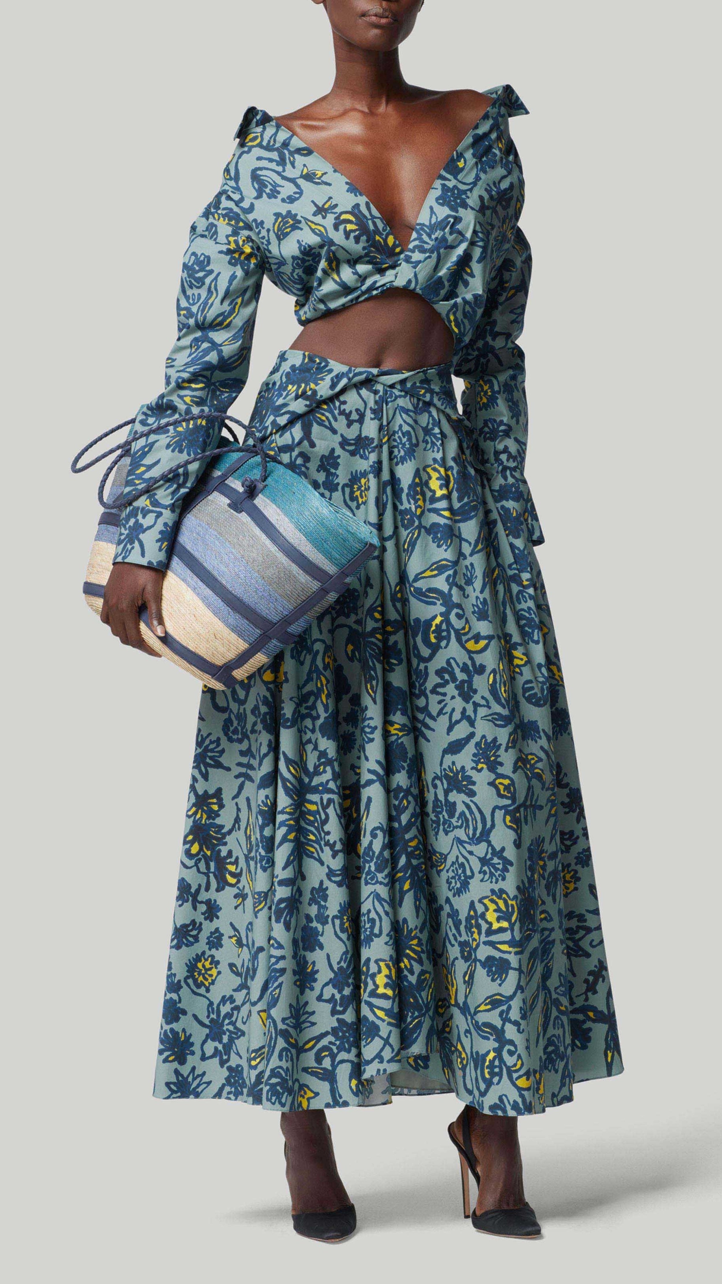 Altuzarra Rhodes Top. Amsonia Shibori Flower in blue, navy and yellow. Crop style with v neck and long sleeves. Can be clasped in the front for more modisty. Photo shown on model facing front with coordinating Pythia Skirt in Amsonia Shibori Flower