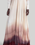 Altuzarra Sif Skirt A tailored maxi skirt with a straight high waistband and a voluminous pleated skirt. Made from 100% Italian silk it is dip dyed in an ombre of in cranberry to ivory coloring. On model facing front.