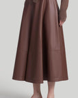 Altuzarra Varda Skirt Made from soft, subtle brown lamb leather, it has an A-line skirt. Midi-length SS24 runway piece. The skirt hem falls to just below the knee. Shown on model facing front and side.