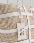 Altuzara Watermill Bag Small in White. Crafted in Mexico from natural palm fibers and detailed with soft white leather. The hand straps are braided leather and it comes with a laser cut detailed Altuzarra hang tag. This photo shows a close up of the details.