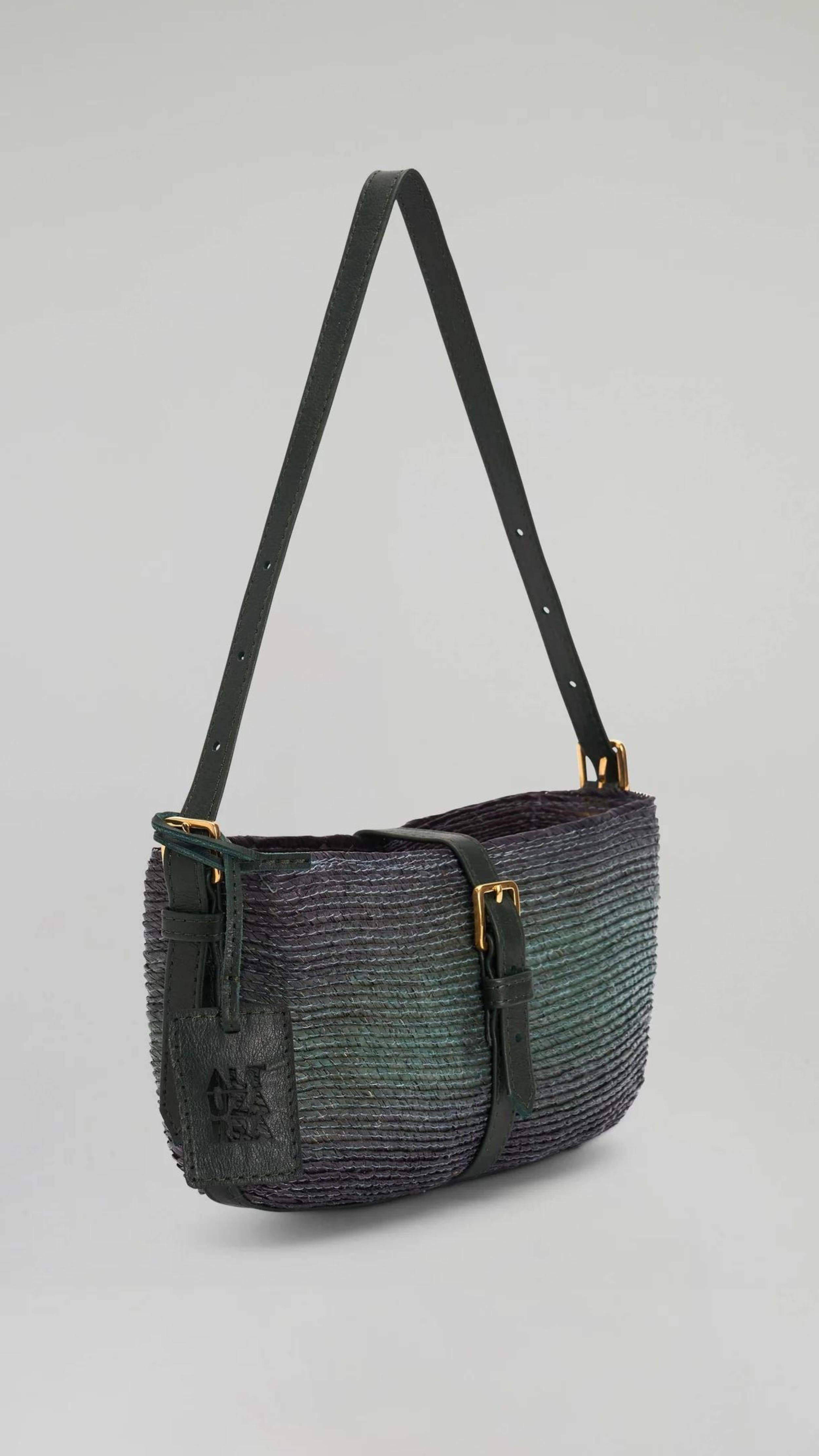 Altuzarra Watermill Shoulder Bag in Campo. Small clutch sized raffia purse in a green and dark blue ombre tone. With navy blue leather details and gold hardware. Photo shown with  front side view. Available at experience 27 in Madrid Spain.
