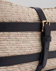 Altuzarra Watermill Shoulder Bag in Natural and Black. Summer raffia clutch with adjustable leather straps. Natural raffia color with black leather detailing and gold hardware. This is a summer purse. Detail photo of leather details and gold strap, Shown facing front and side view. Available with Experience 27 in Madrid Spain