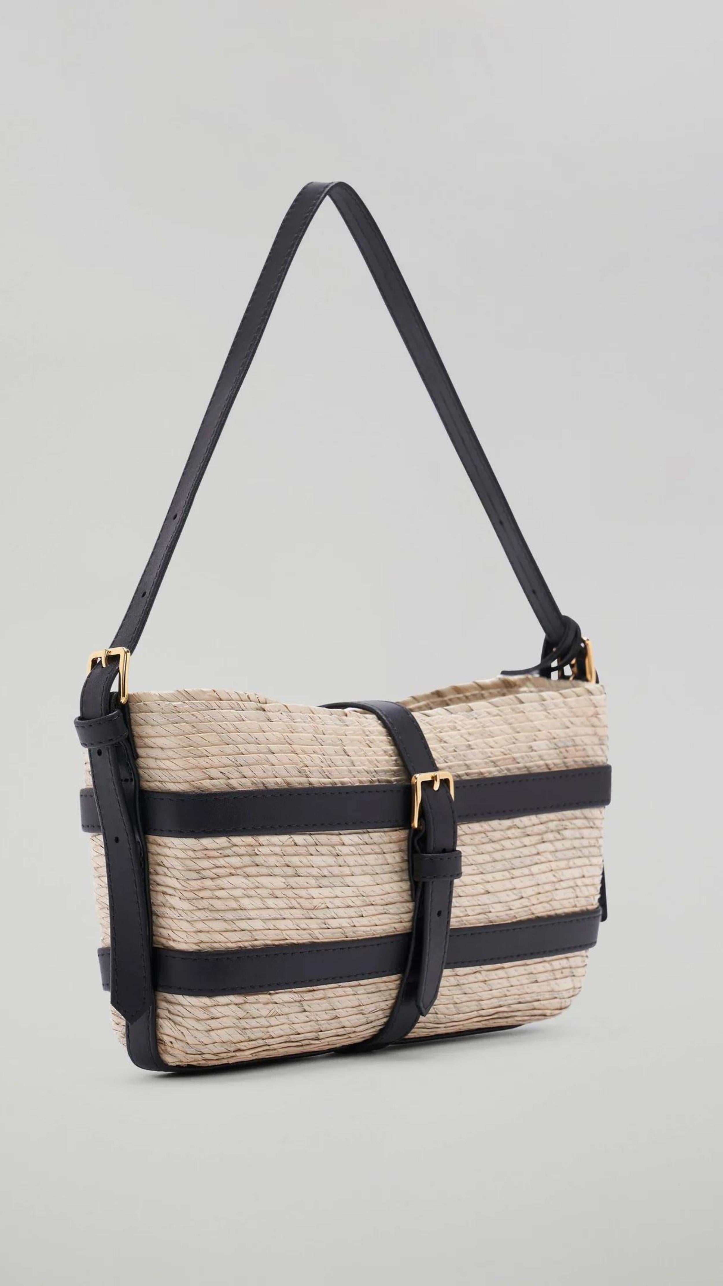 Altuzarra Watermill Shoulder Bag in Natural and Black. Summer raffia clutch with adjustable leather straps. Natural raffia color with black leather detailing and gold hardware. This is a summer purse. Shown facing front view. Available with Experience 27 in Madrid Spain